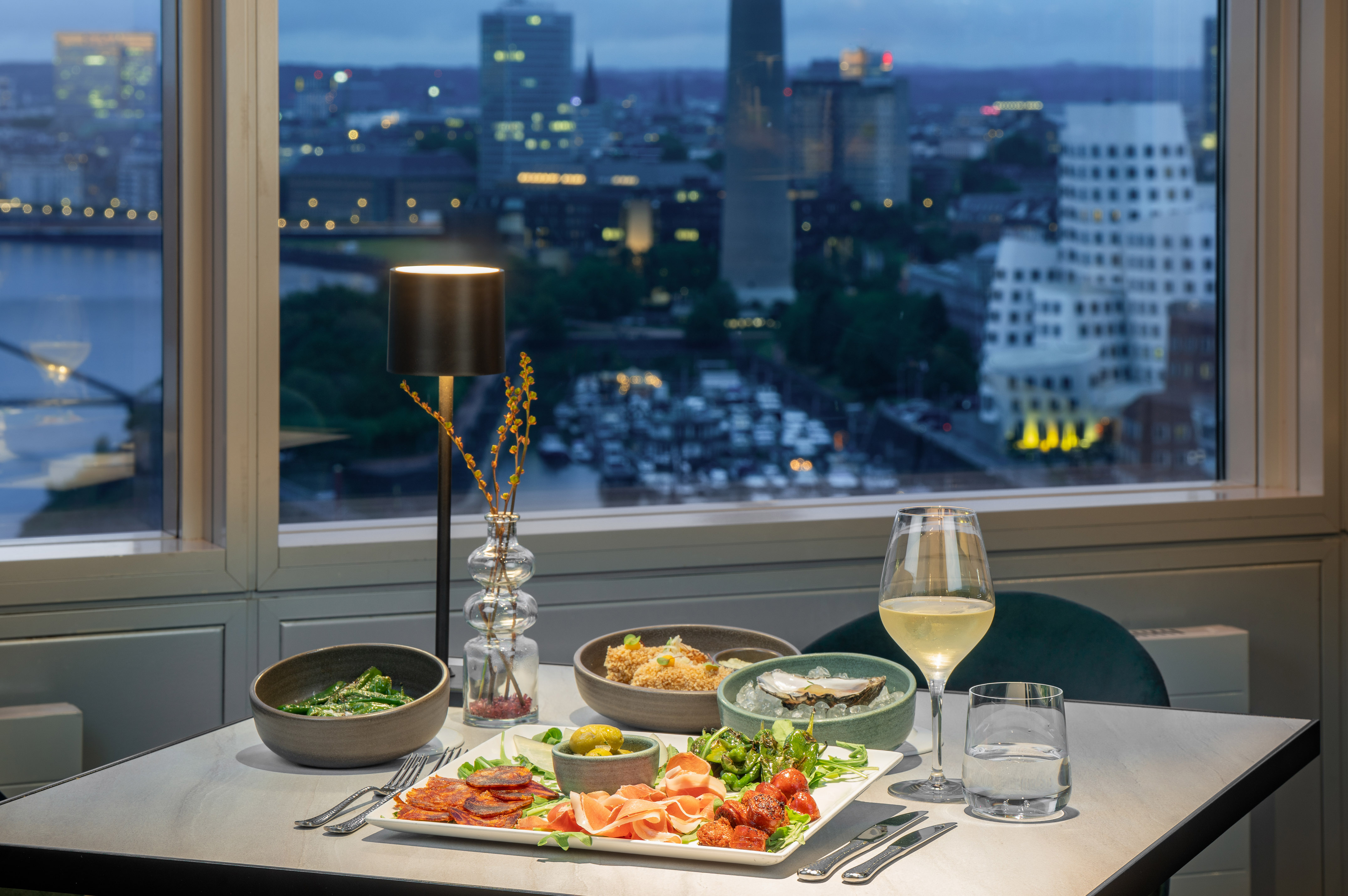 Charcuterie, oysters, wine, and city skyline view from a restaurant.