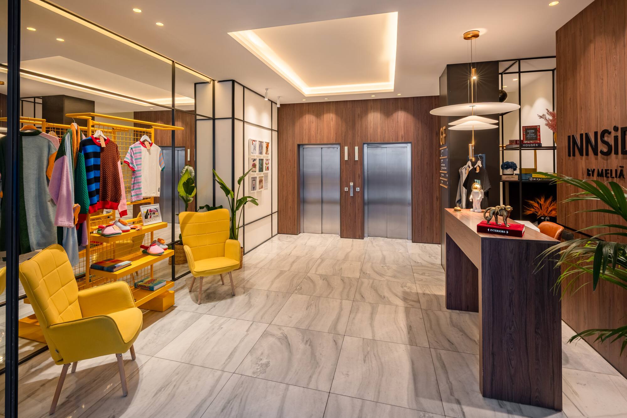 INNSiDE by Meliá hotel lobby with elevators, reception, and modern retail area.