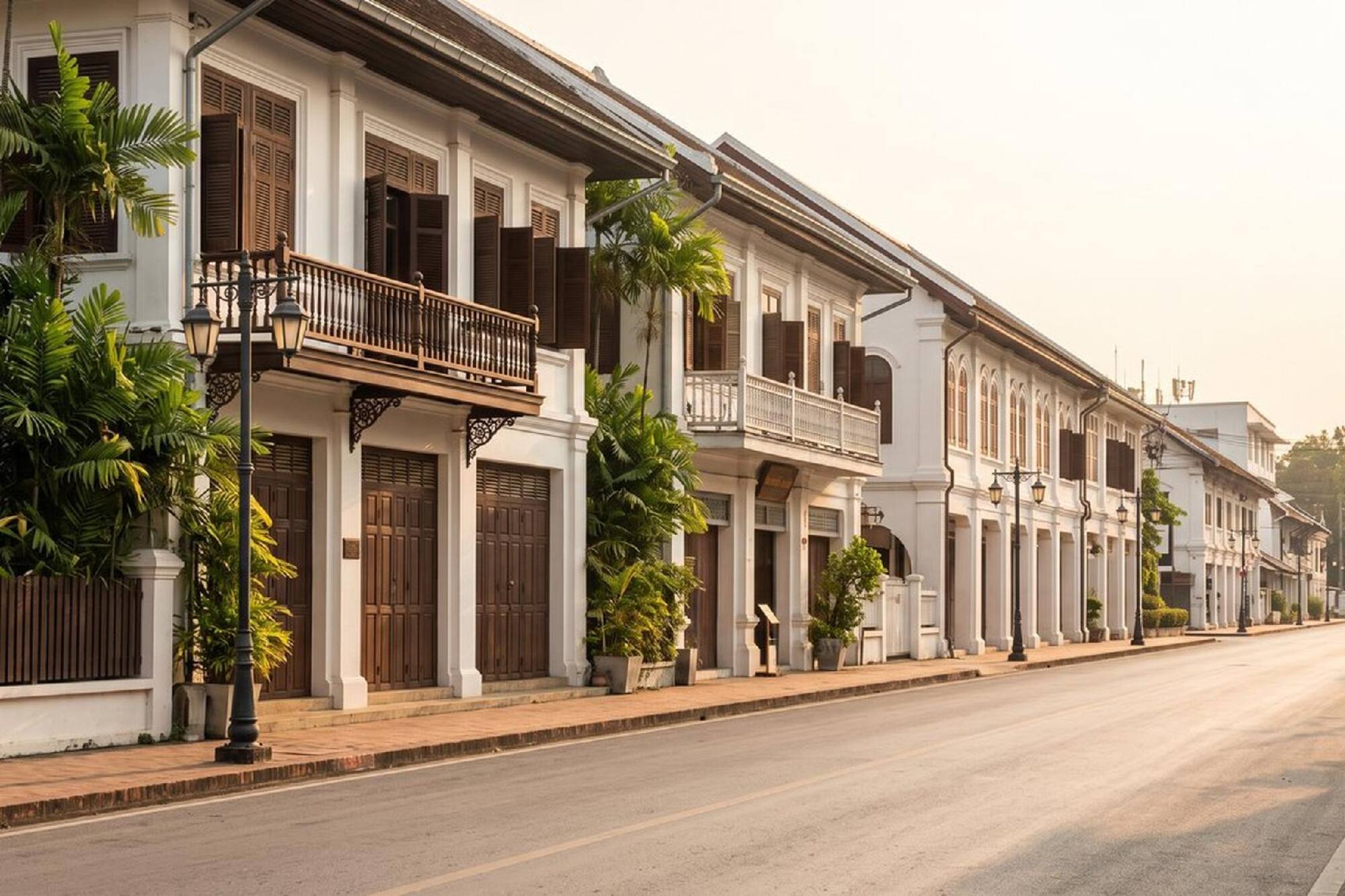 Calle con edificios coloniales blancos, balcones y palmeras.