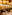 Luxury restaurant dining room with warm lighting, golden decor, and set tables.