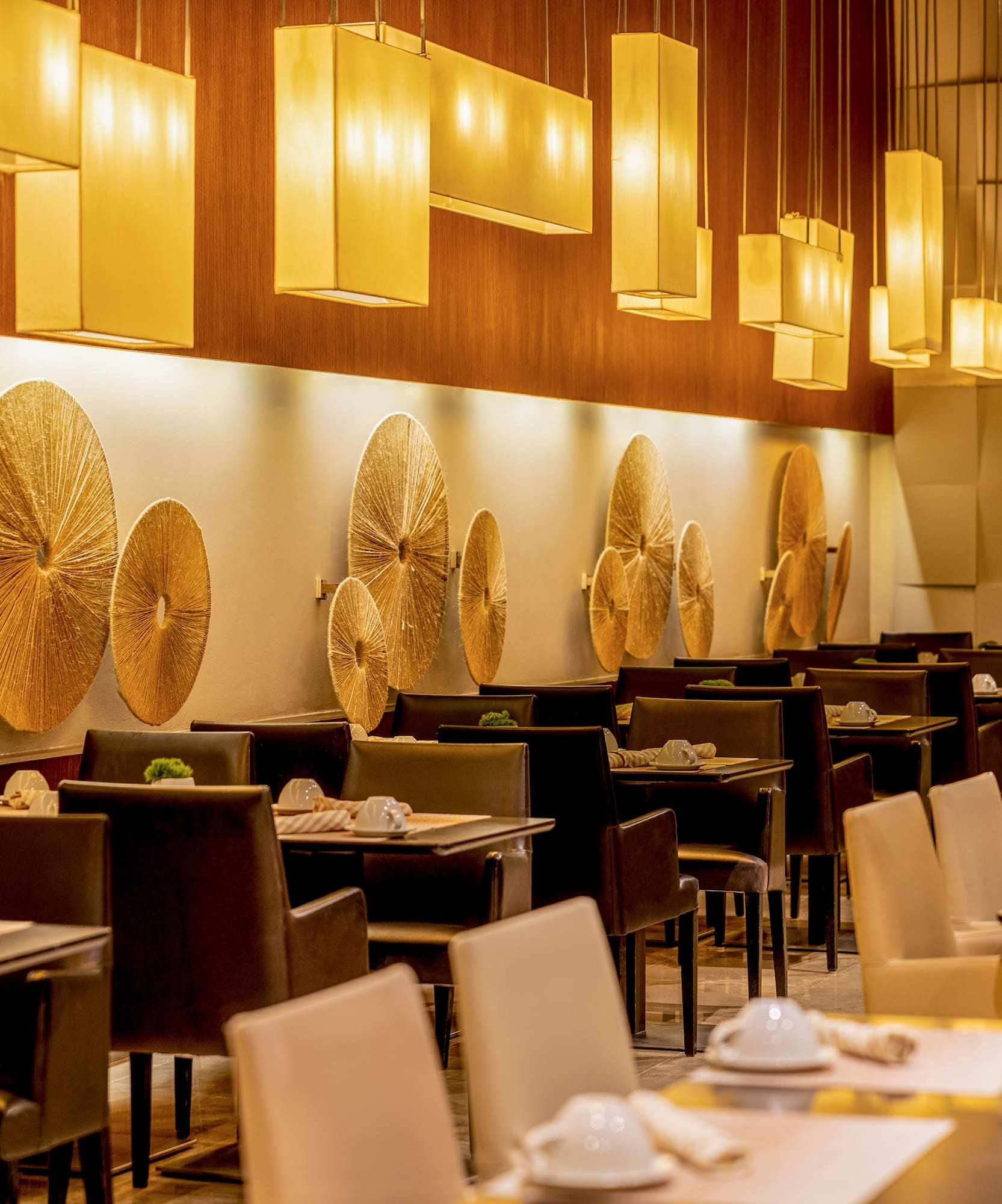 Luxury restaurant dining room with warm lighting, golden decor, and set tables.