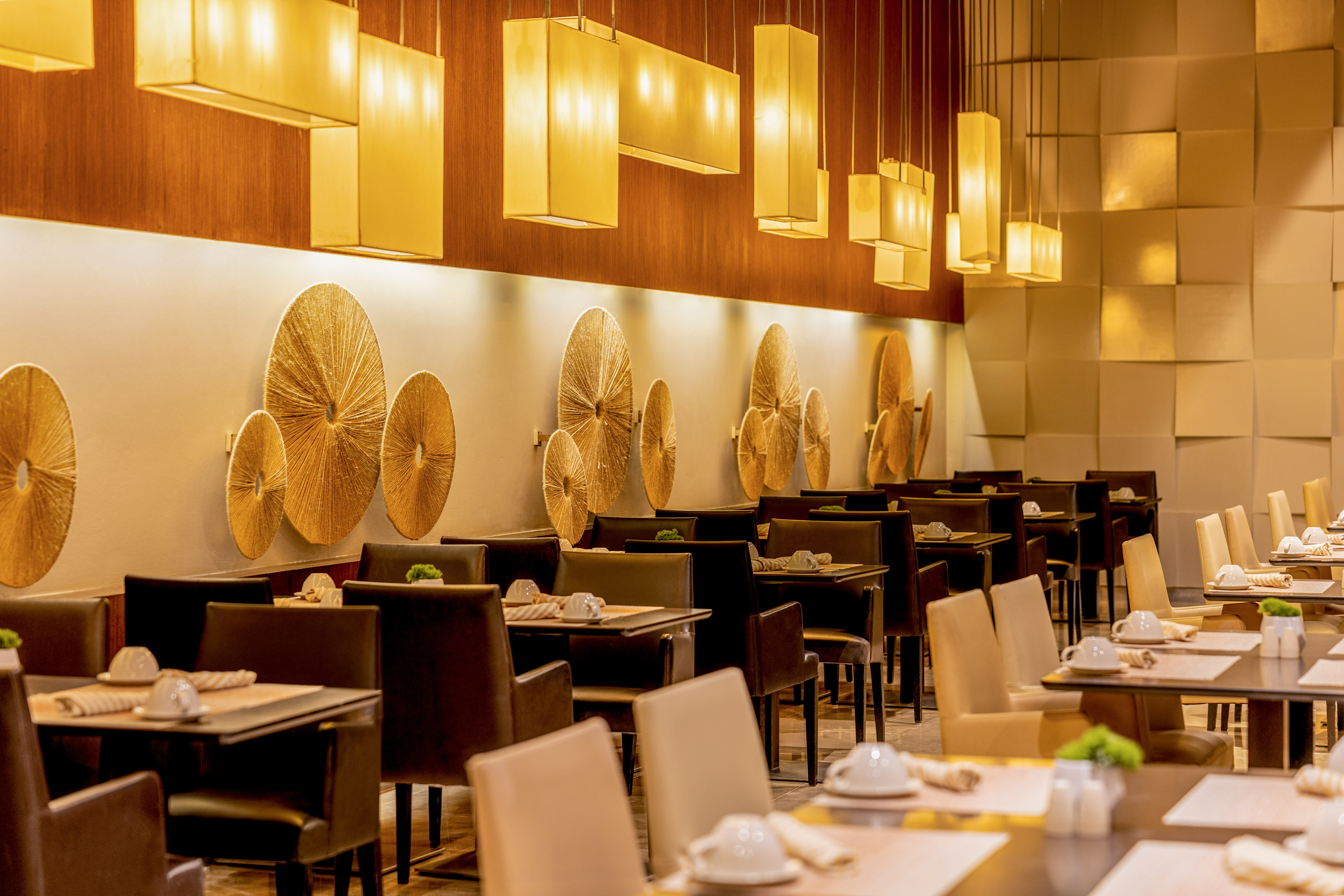 Luxury restaurant dining room with warm lighting, golden decor, and set tables.