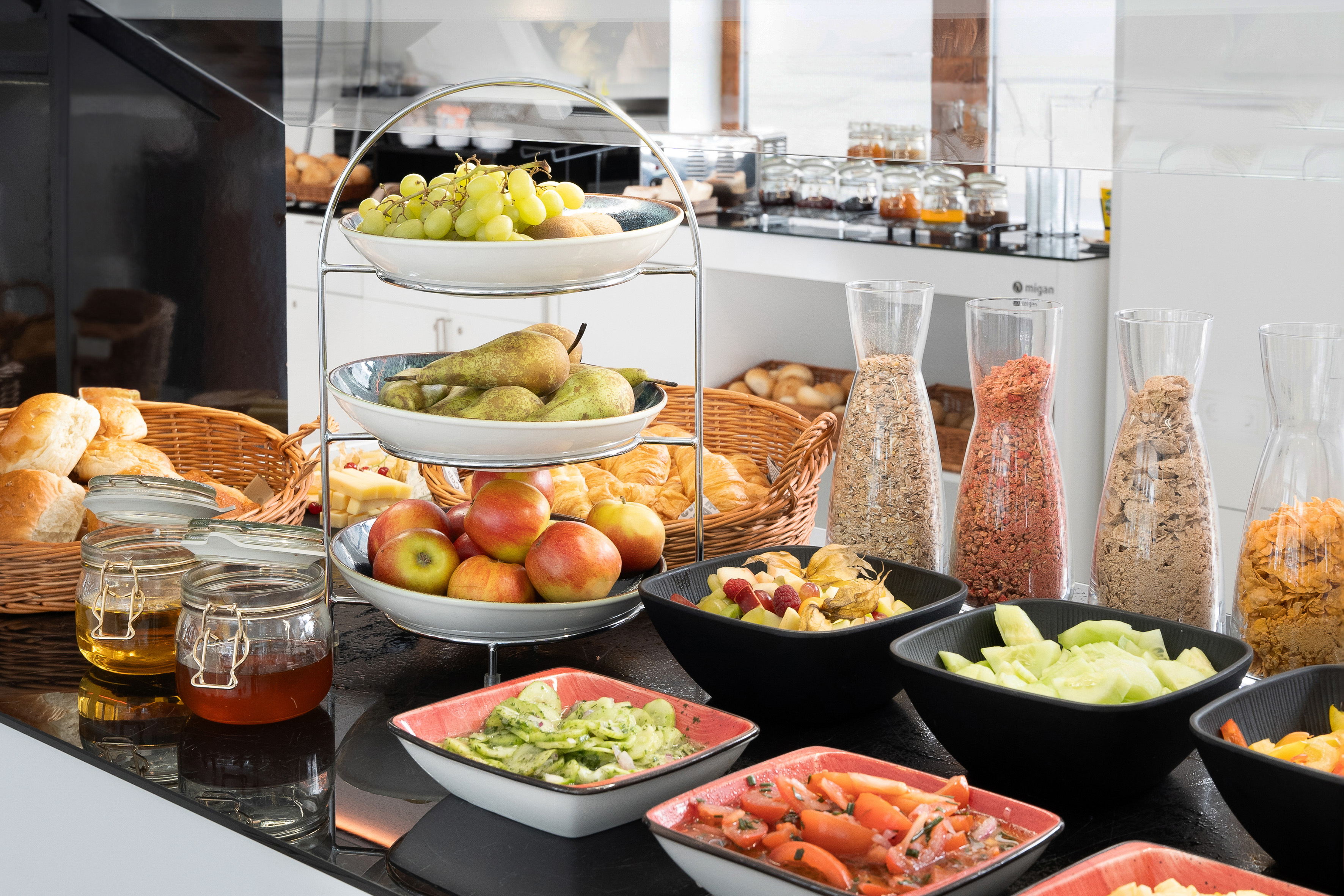 Healthy breakfast buffet featuring fresh fruit, pastries, cereals, and salads.