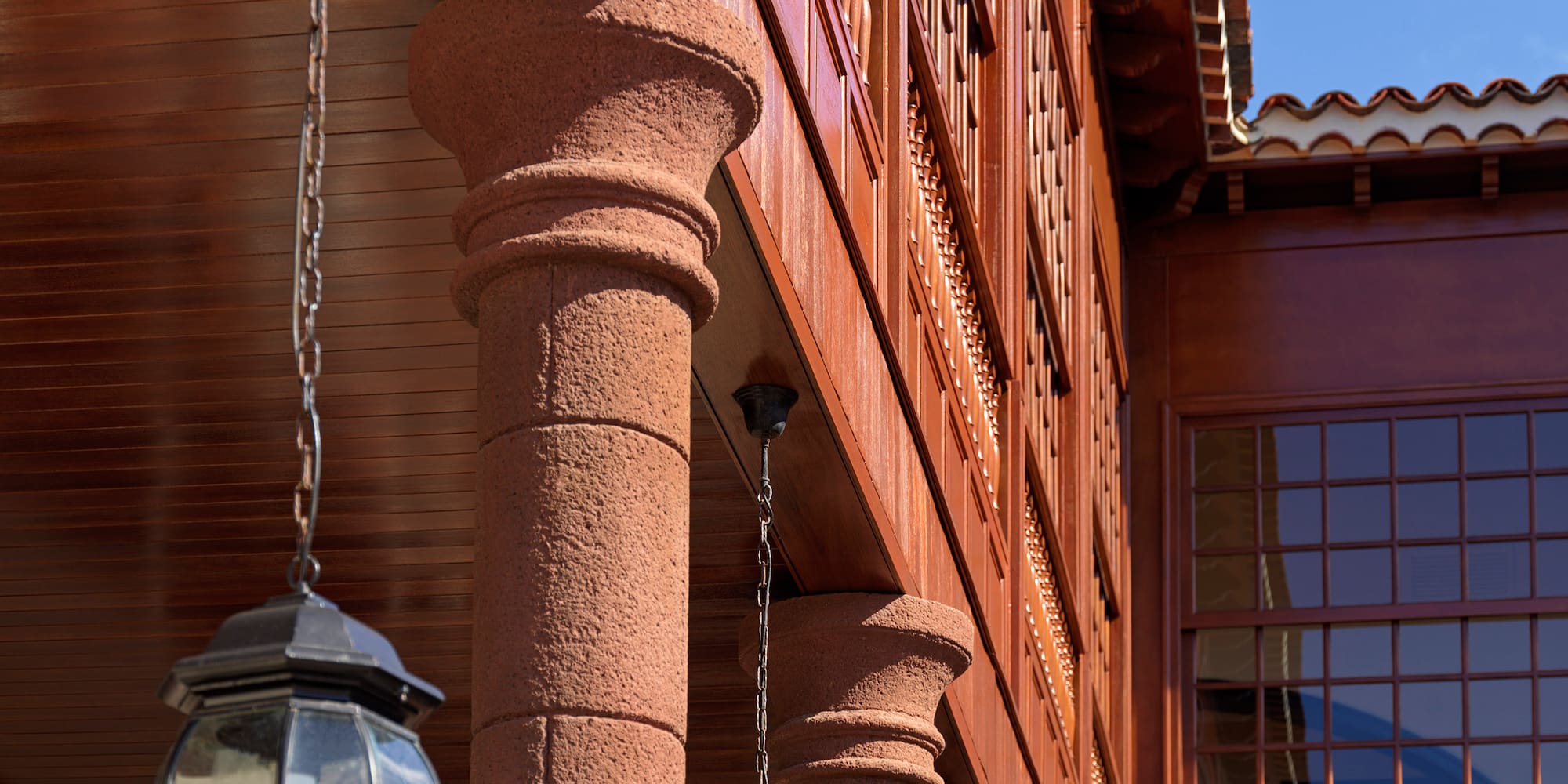 Spanish colonial architecture: wooden balcony, stone columns, hanging lanterns.