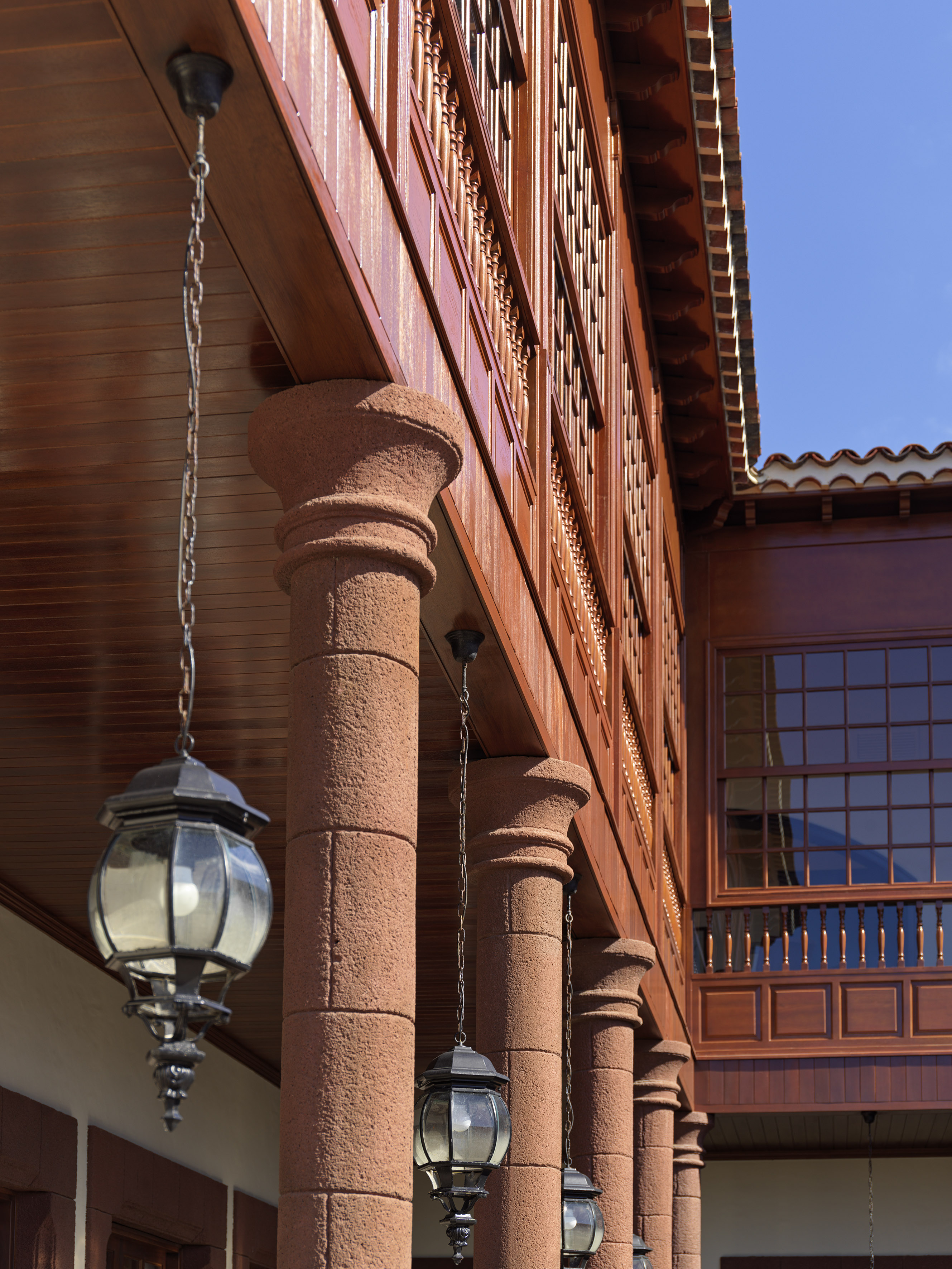 Spanish colonial architecture: wooden balcony, stone columns, hanging lanterns.