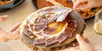 a group of hands holding a plate of meat
