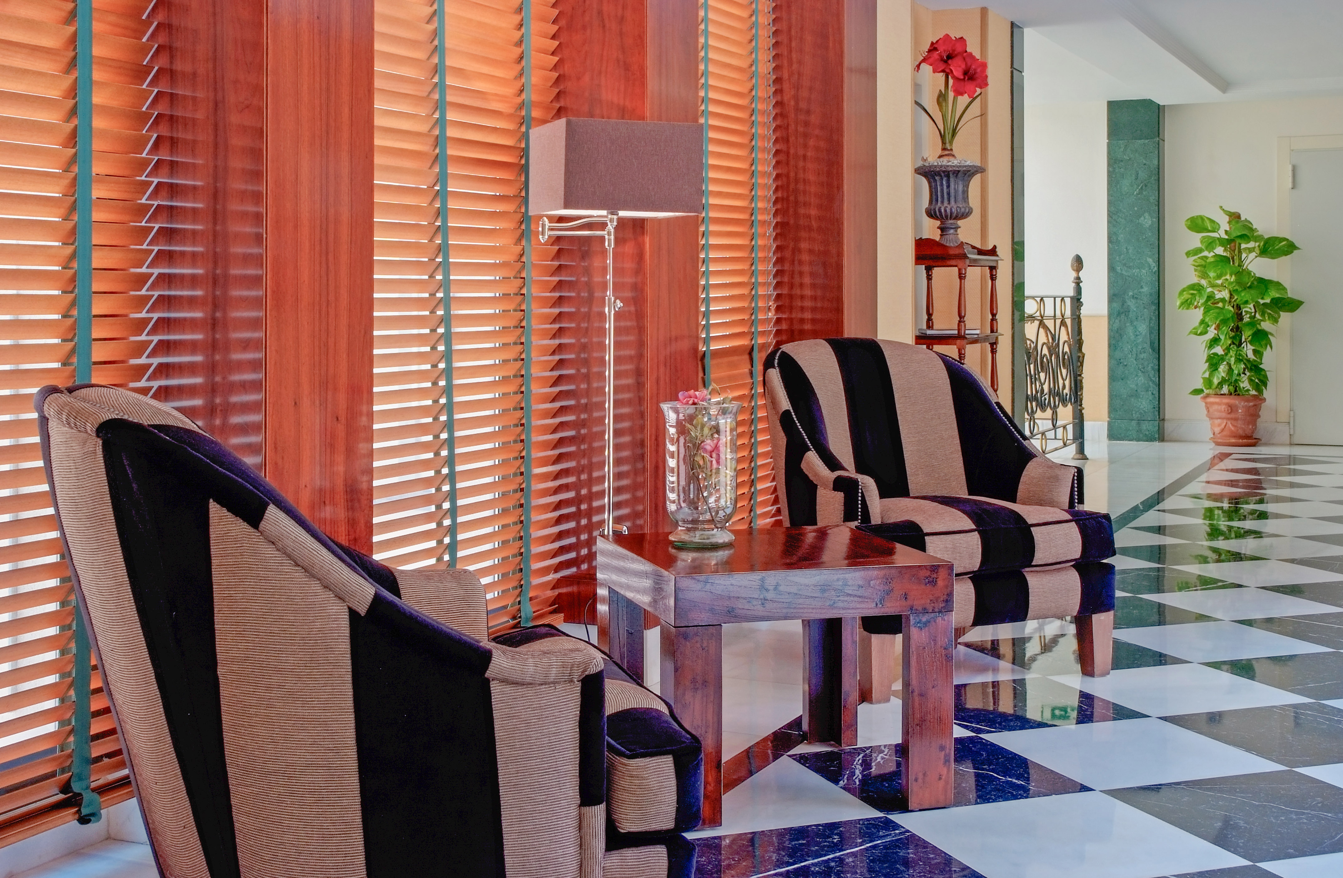Salón de hotel con sillones a rayas, persianas madera y suelo ajedrezado. - Meliá Recoletos, Valladolid