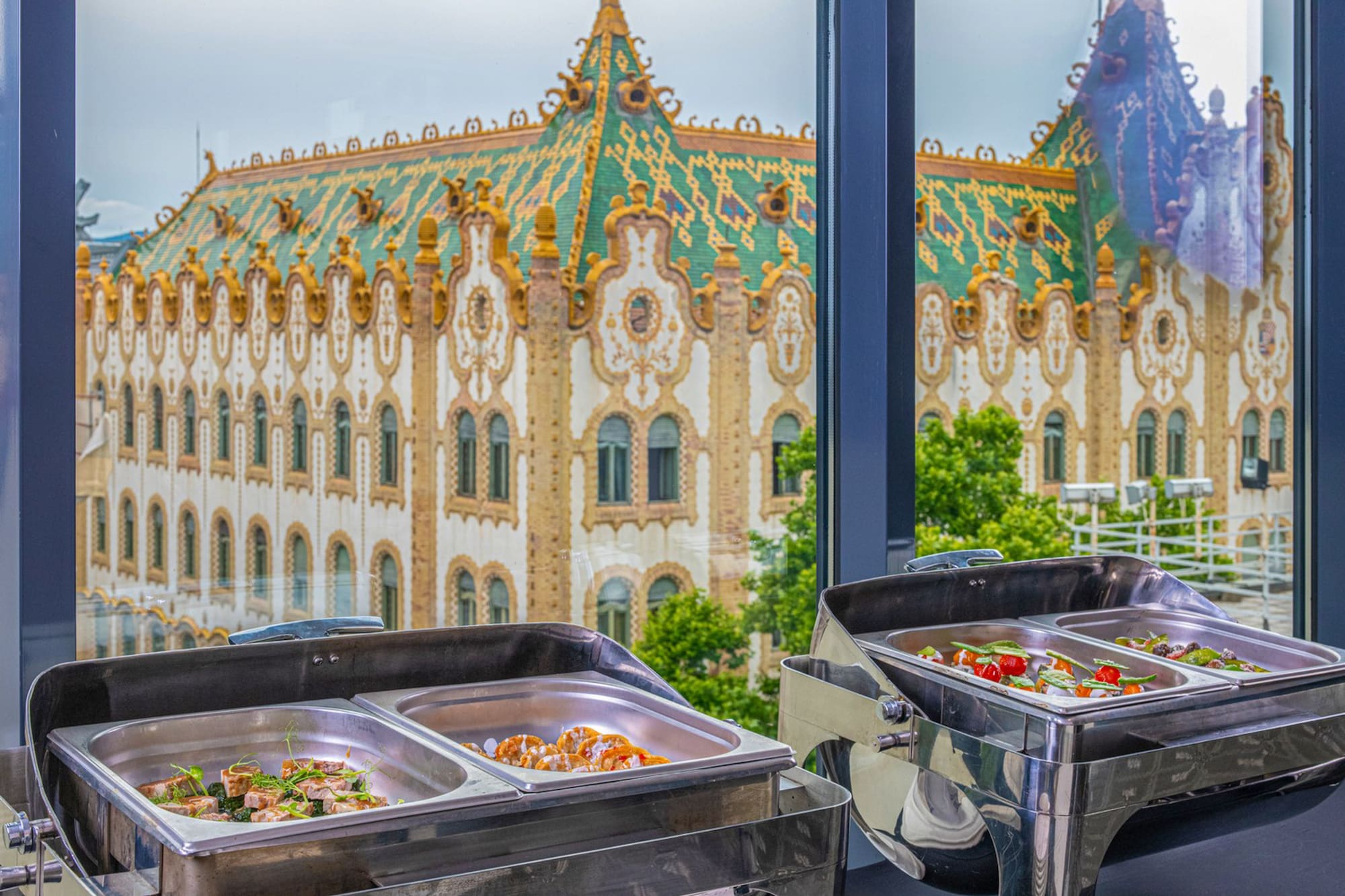 Catering buffet in foreground, ornate Budapest Art Nouveau building behind.