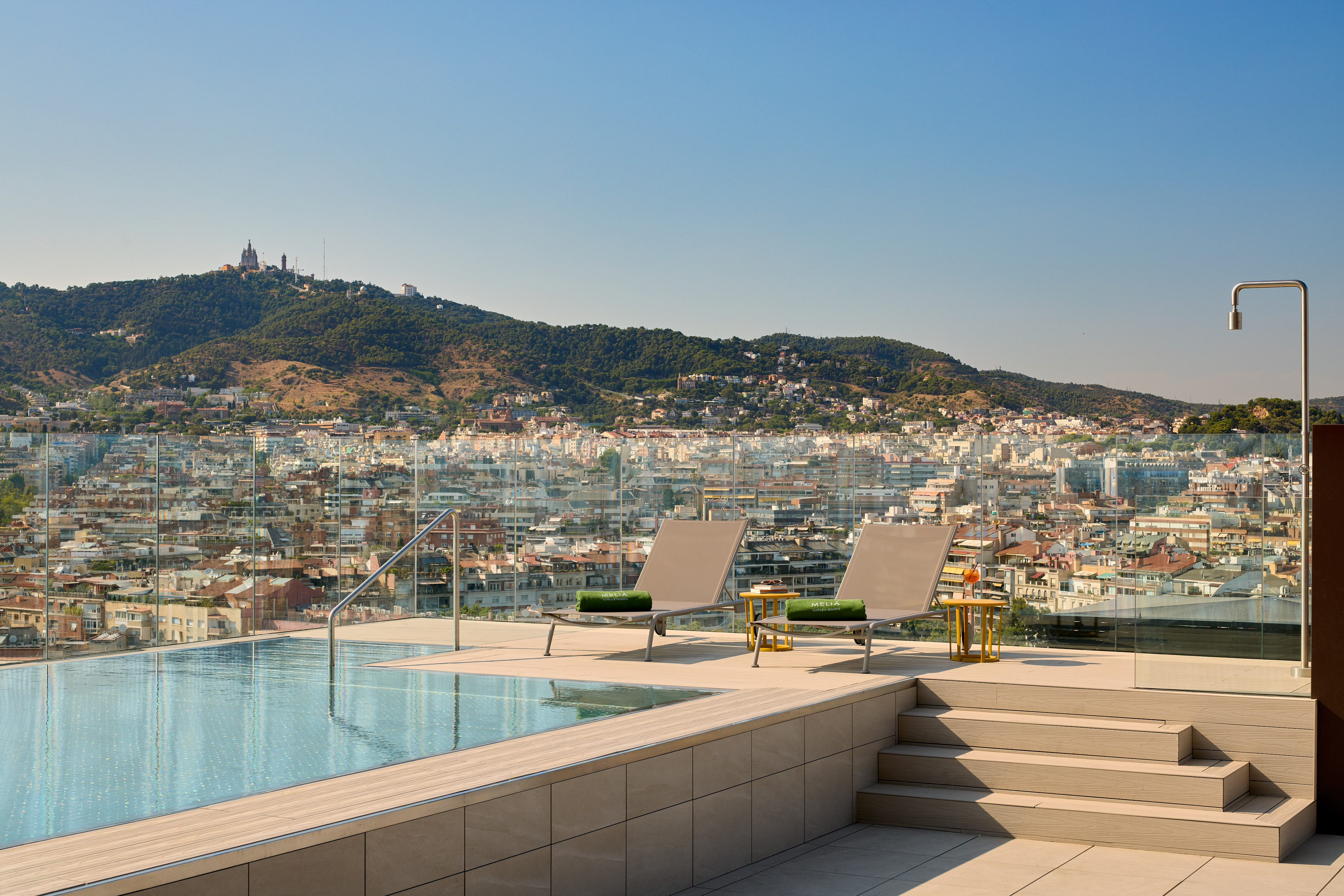 Piscina en azotea de hotel con vistas a Barcelona y el Tibidabo.