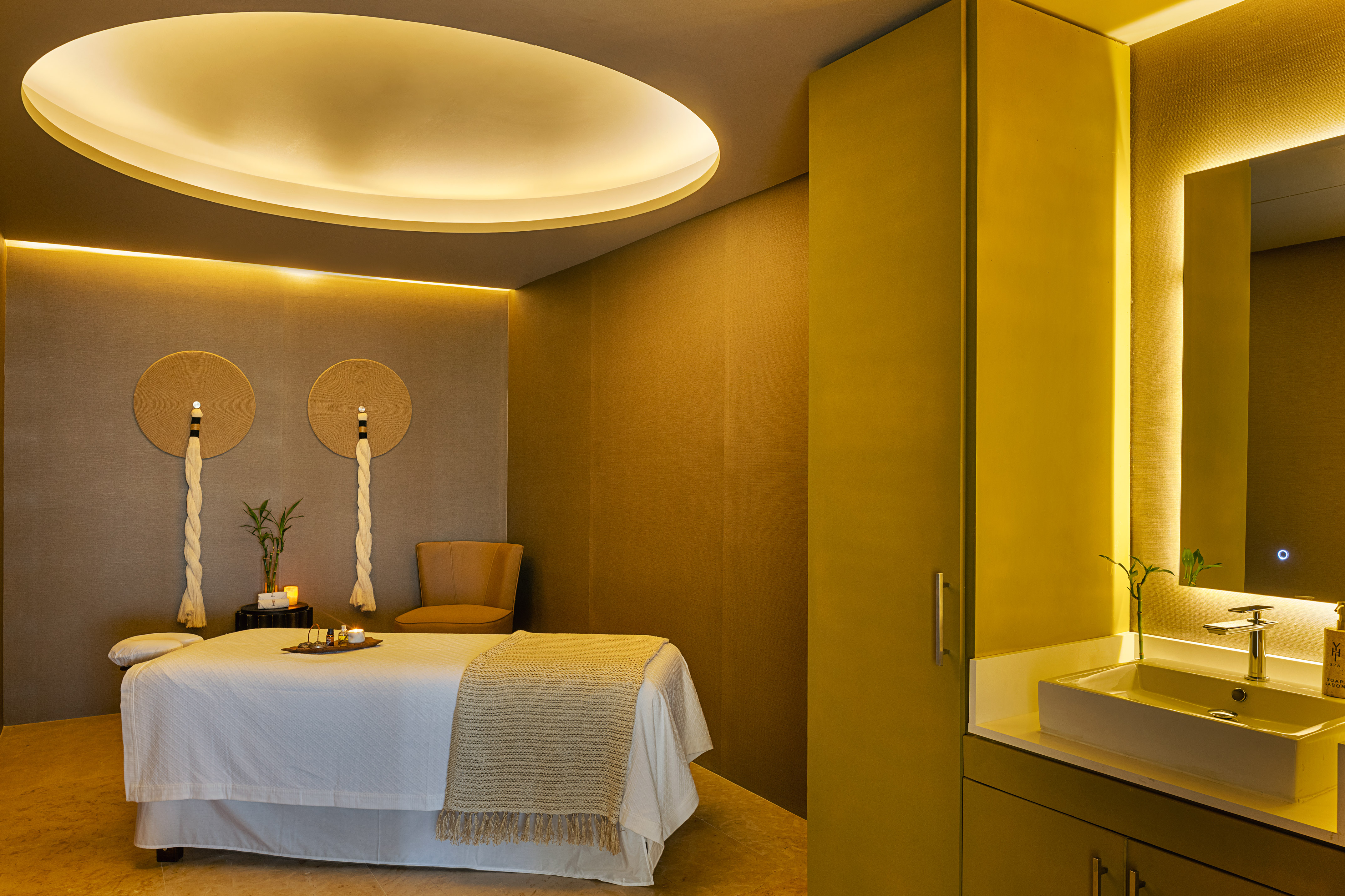 Serene spa treatment room with massage bed, warm lighting, and private vanity.