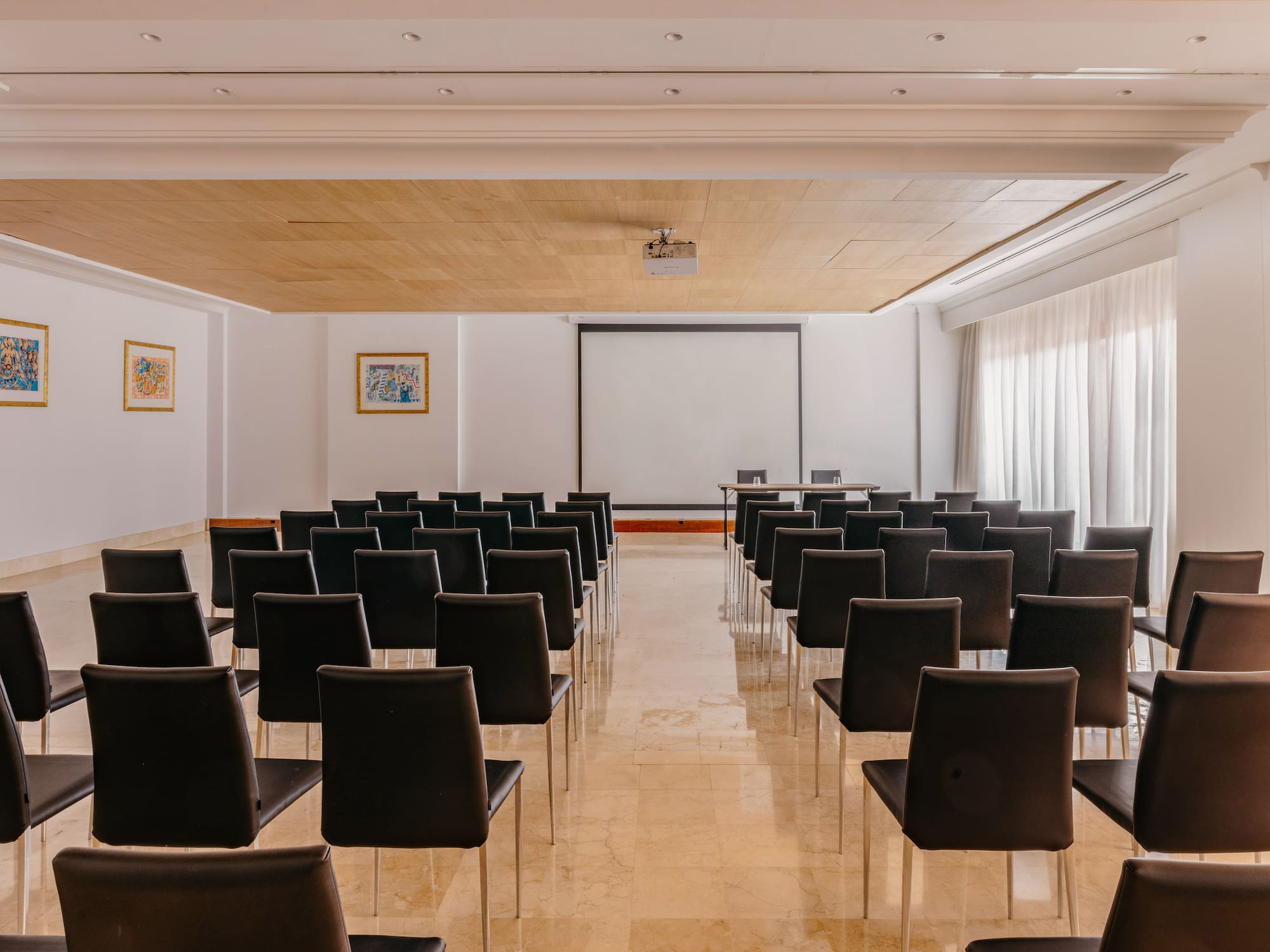 Empty conference room with rows of chairs, projector screen, and presentation setup.