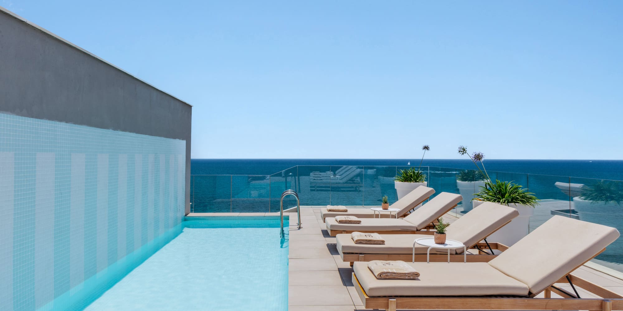 a pool with lounge chairs and a deck chair on a rooftop