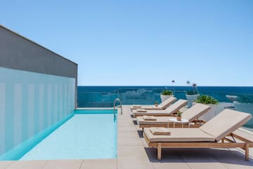 a pool with lounge chairs and a deck chair on a rooftop