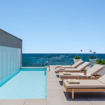 a pool with lounge chairs and a deck chair on a rooftop