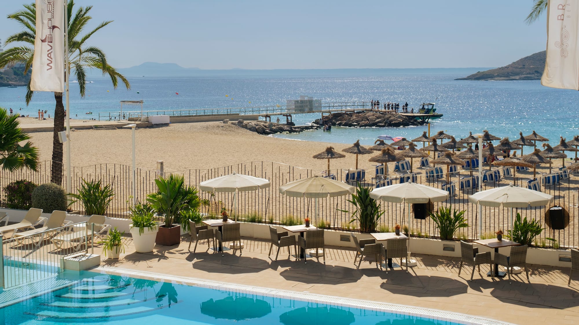 a pool with umbrellas and chairs on a beach