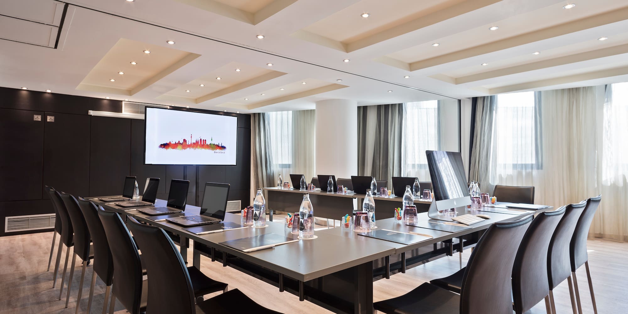 a conference room with a large table with laptops and chairs