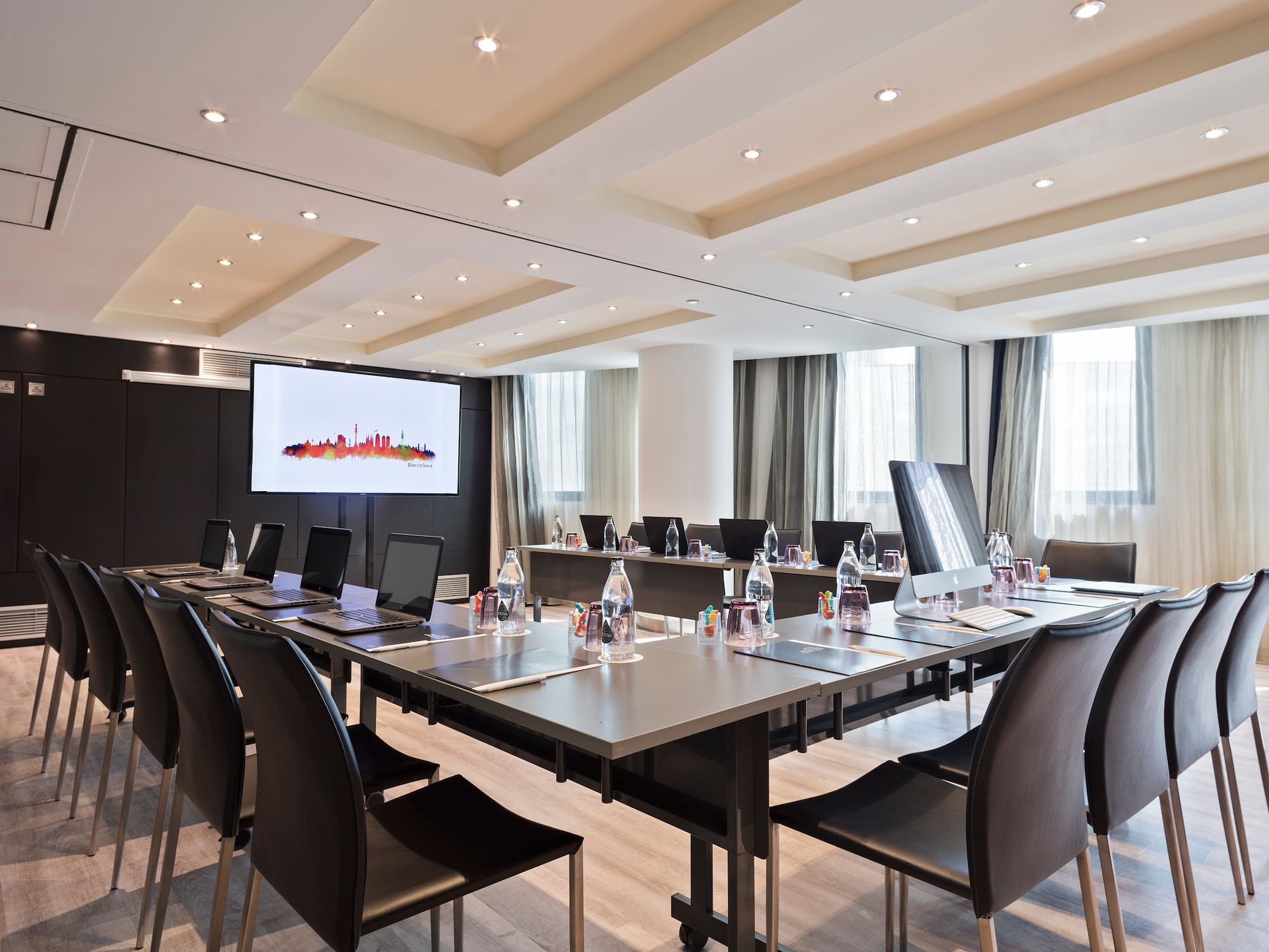 a conference room with a large table with laptops and chairs