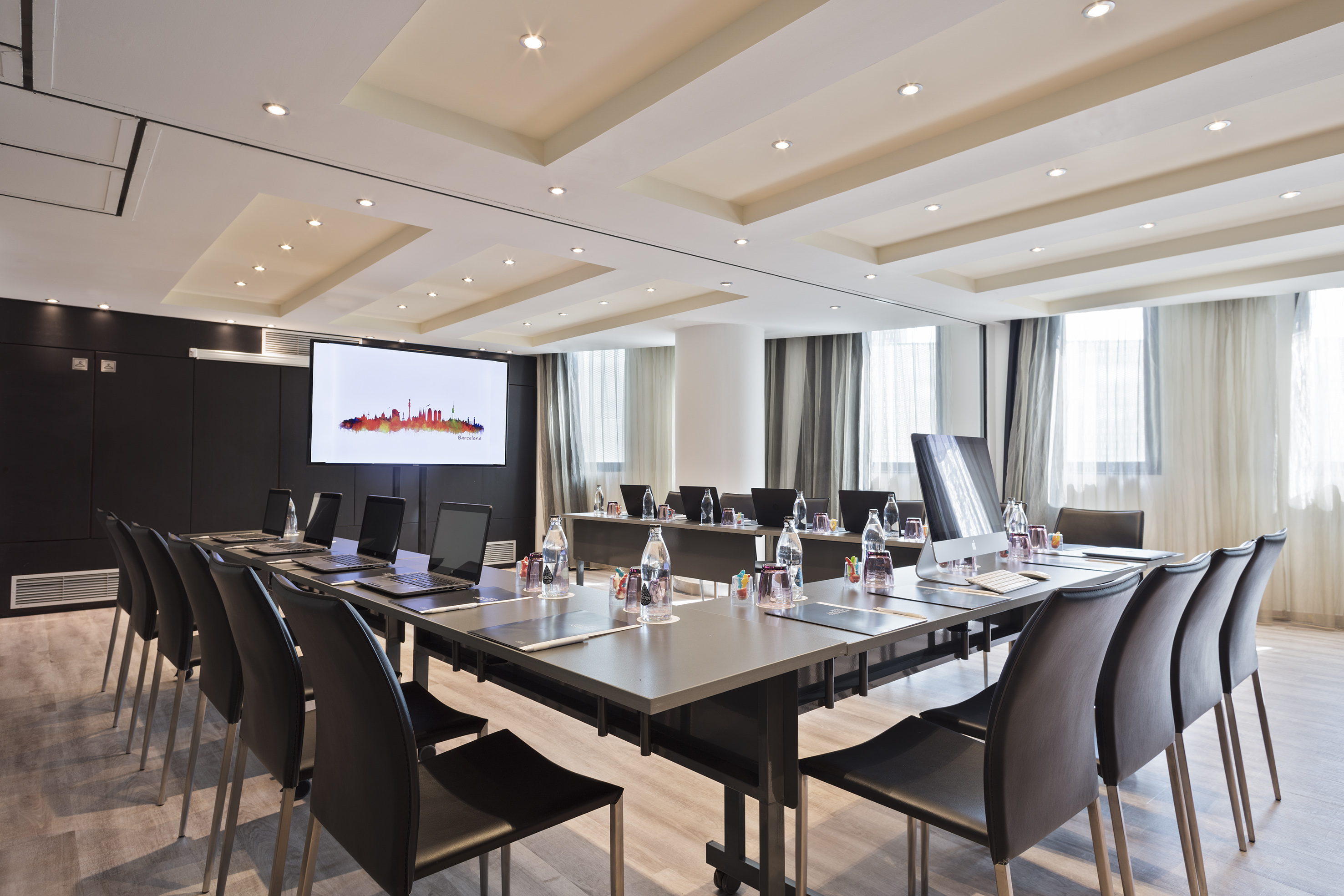 a conference room with a large table with laptops and chairs
