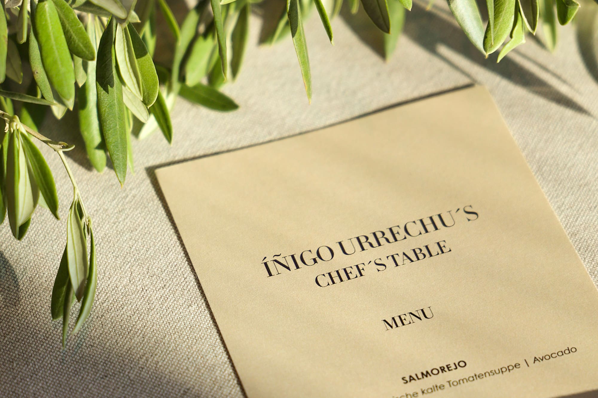 Íñigo Urrechu's Chef's Table menu, featuring an olive branch and sunlight.
