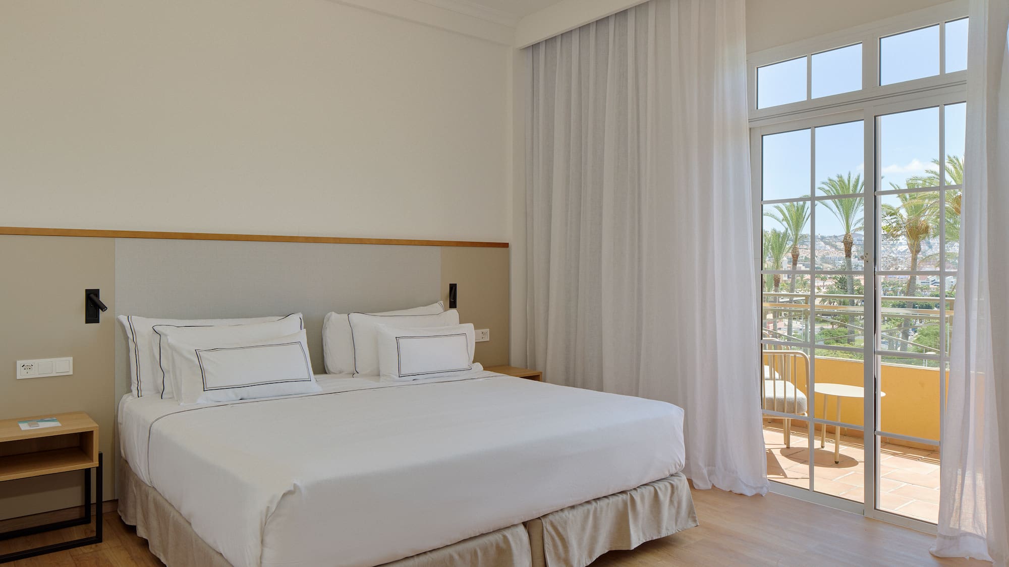 a bed with white sheets and a glass door