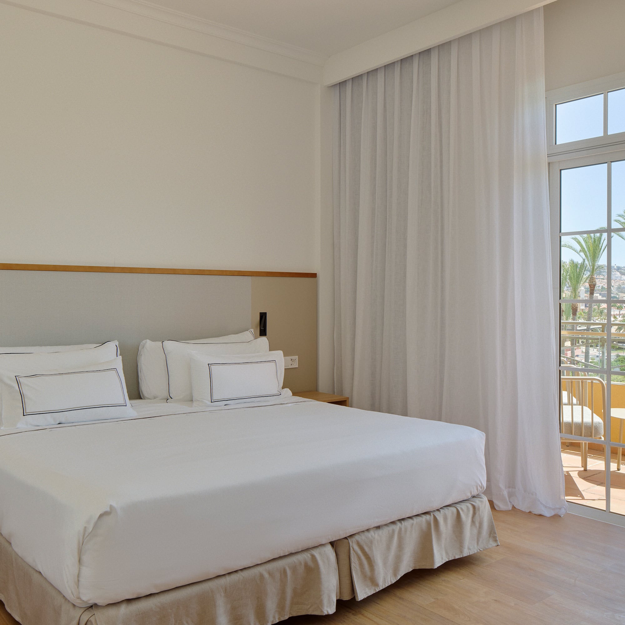 a bed with white sheets and a glass door