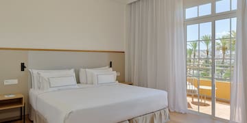 a bed with white sheets and a glass door