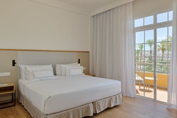 a bed with white sheets and a glass door