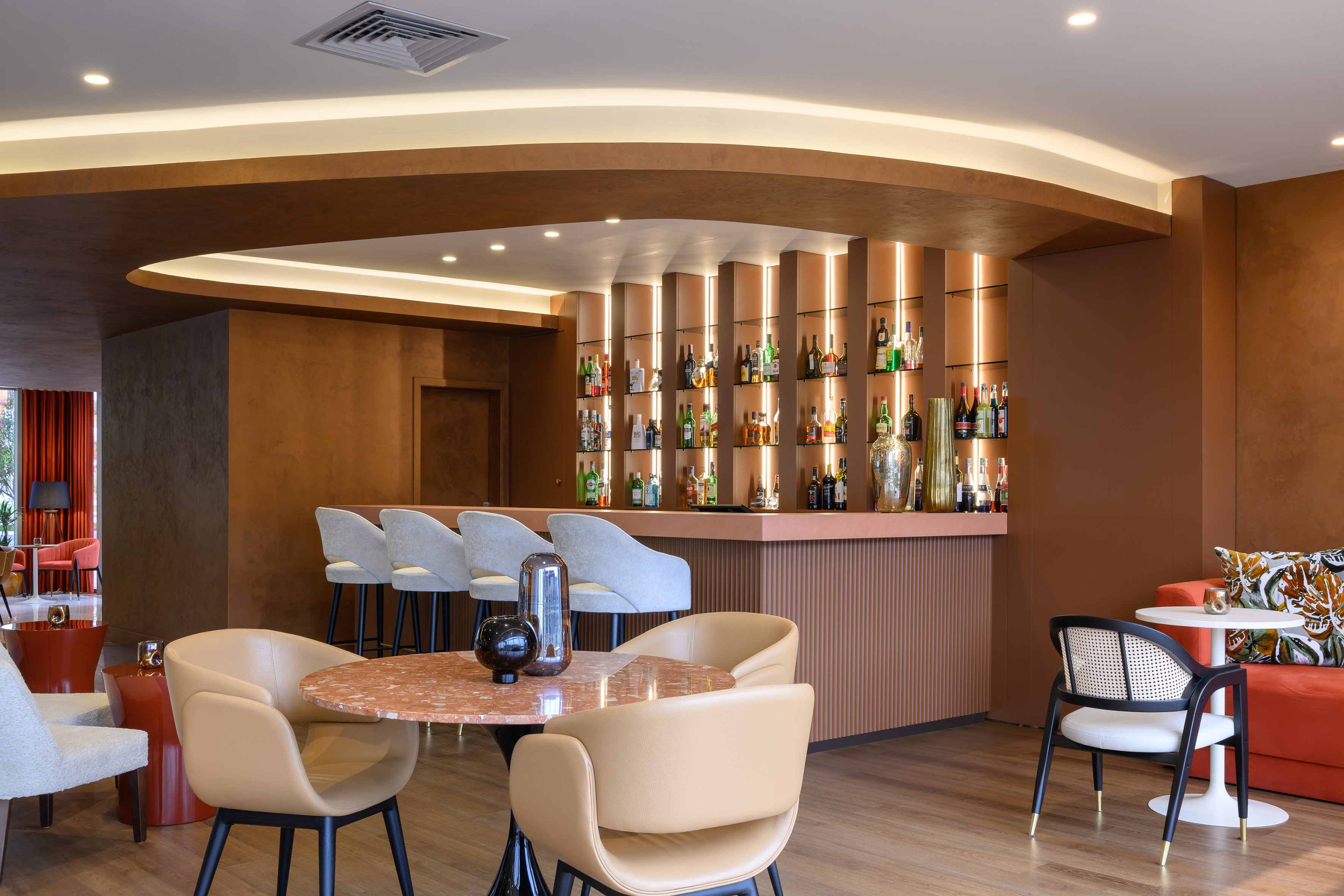 Bronze tone hotel bar with illuminated bottle display and modern lounge seating.