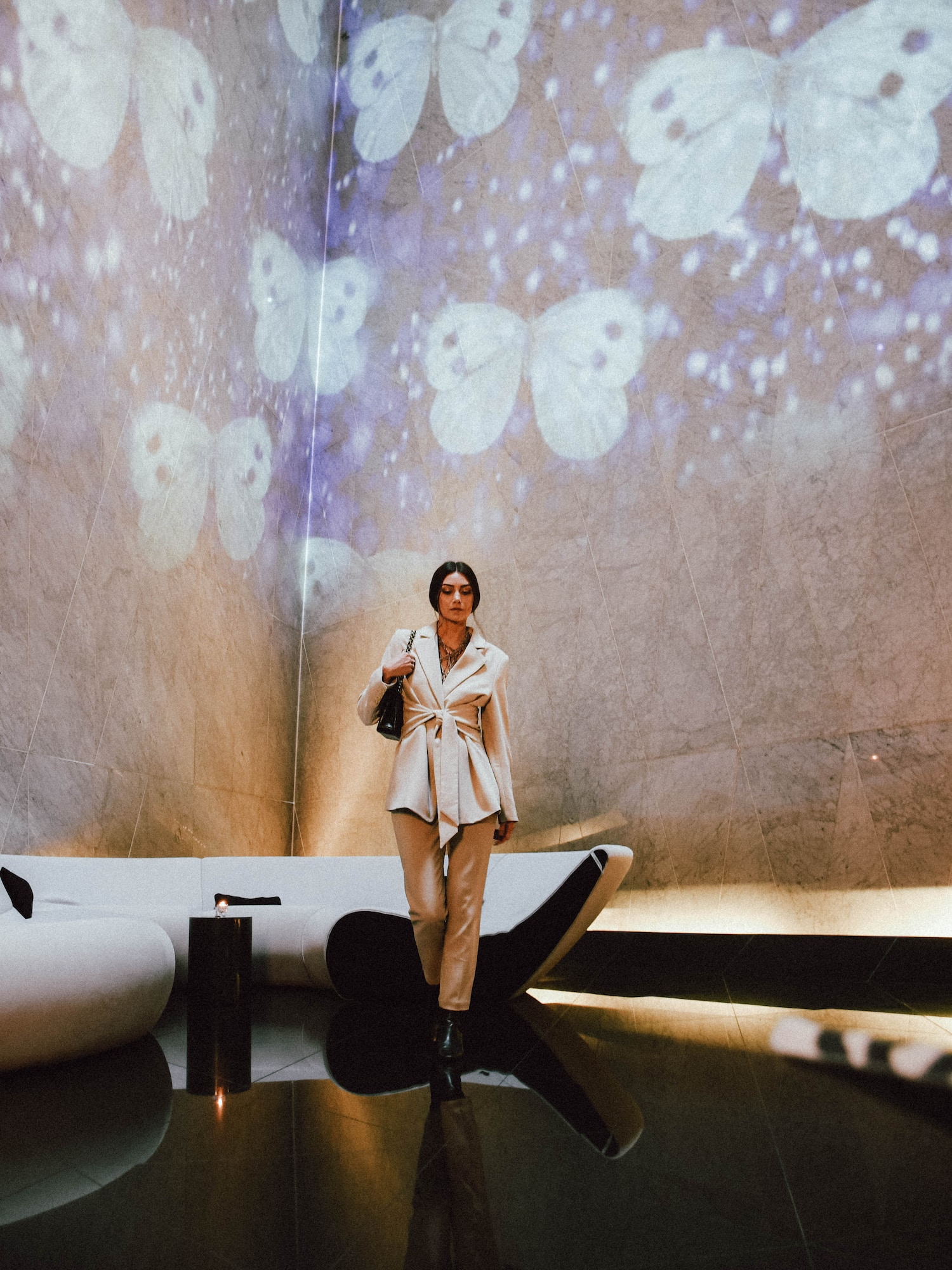 a woman standing in a room with a wall of butterflies
