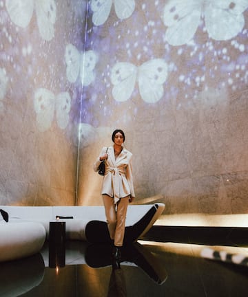 a woman standing in a room with a wall of butterflies