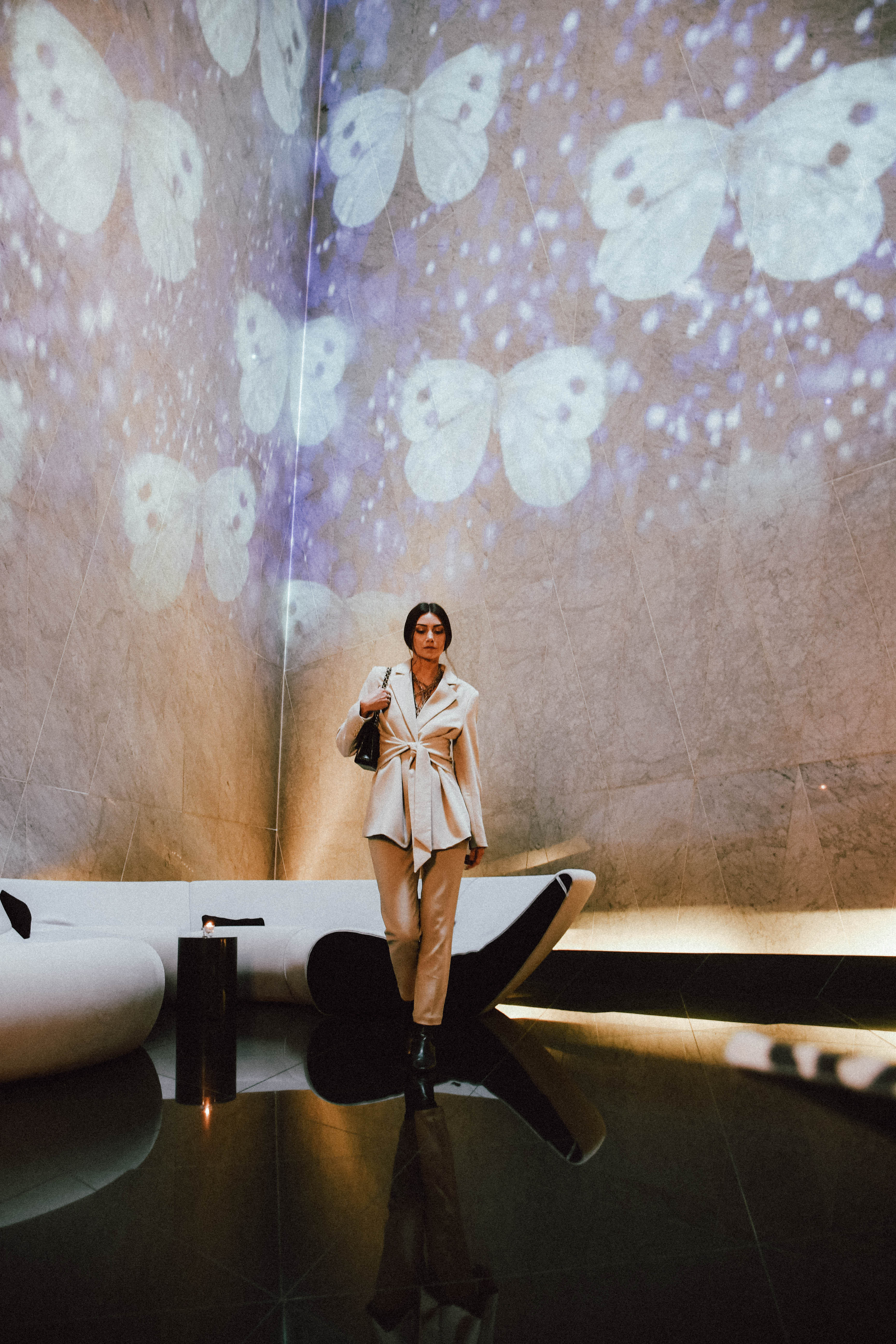 a woman standing in a room with a wall of butterflies