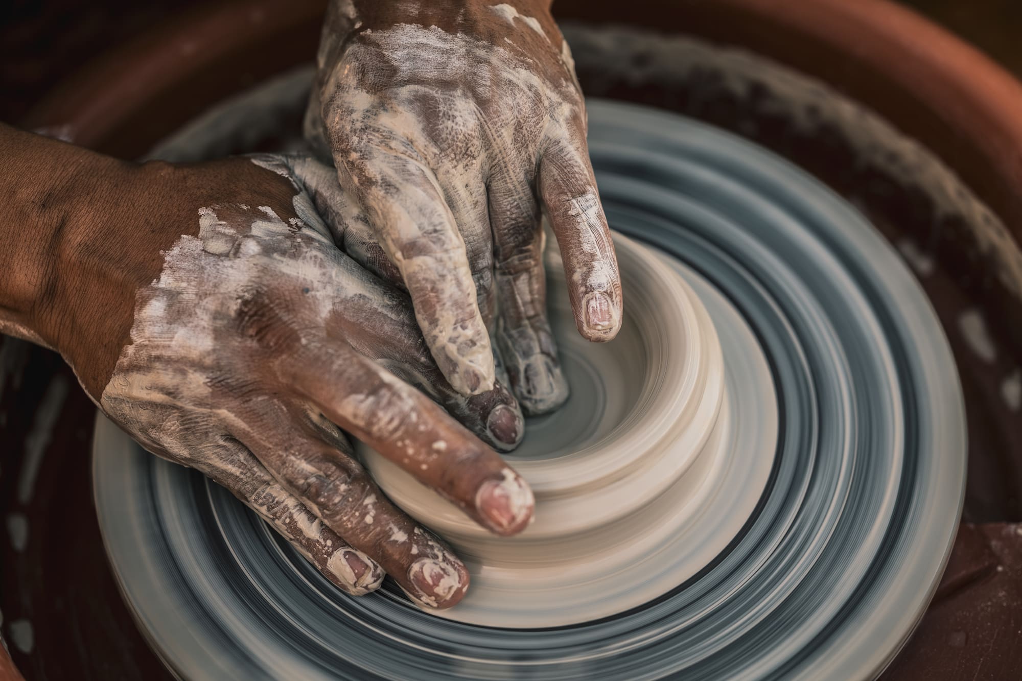 a person's hands making a clay pot
