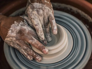 a person's hands making a clay pot
