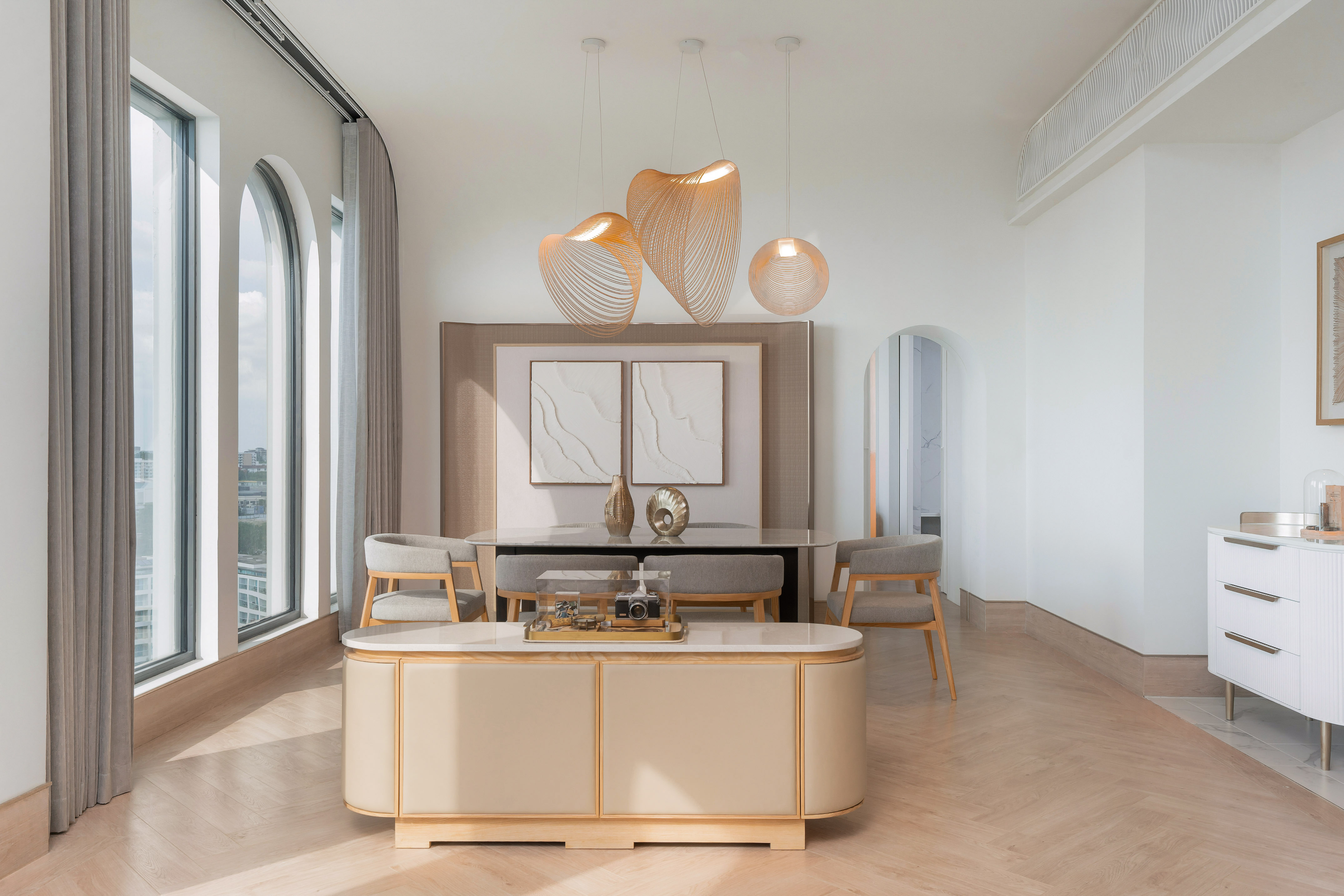 Modern dining area with arched windows, sculptural pendant lights, wood floor.