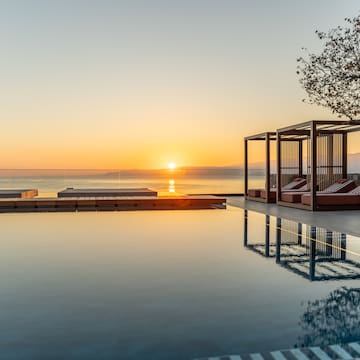 a pool with a gazebo and a tree and a sunset