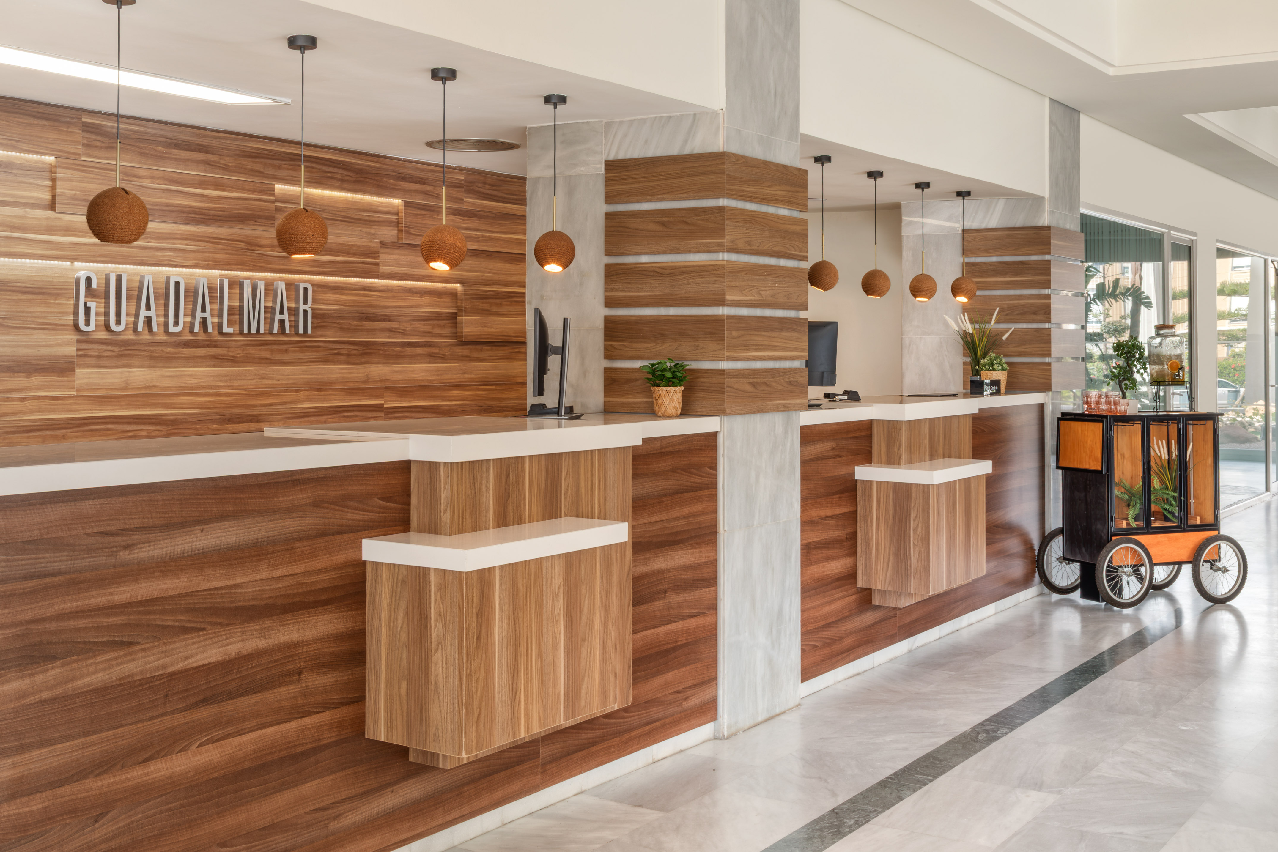 GUADALMAR hotel reception with modern wooden desks and pendant lights.