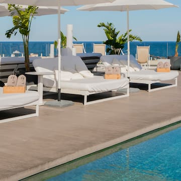 a pool with white lounge chairs and umbrellas