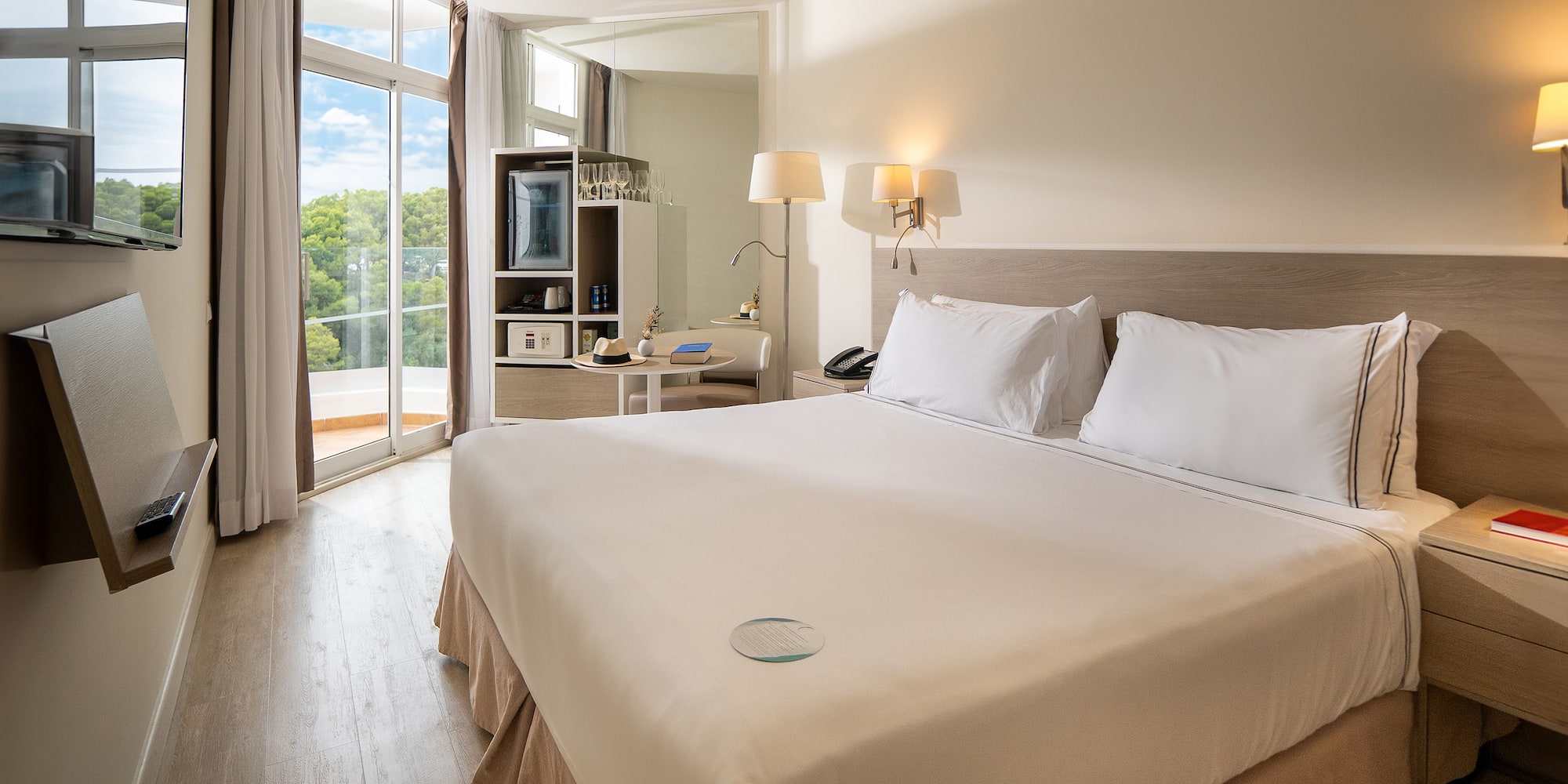 a bed with white sheets and lamps in a room with a glass door