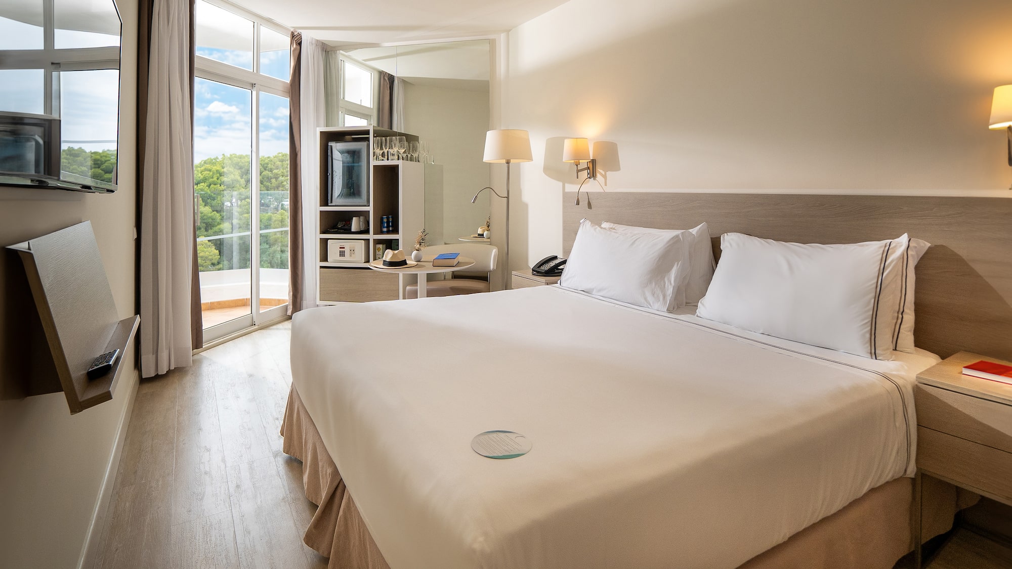 a bed with white sheets and lamps in a room with a glass door
