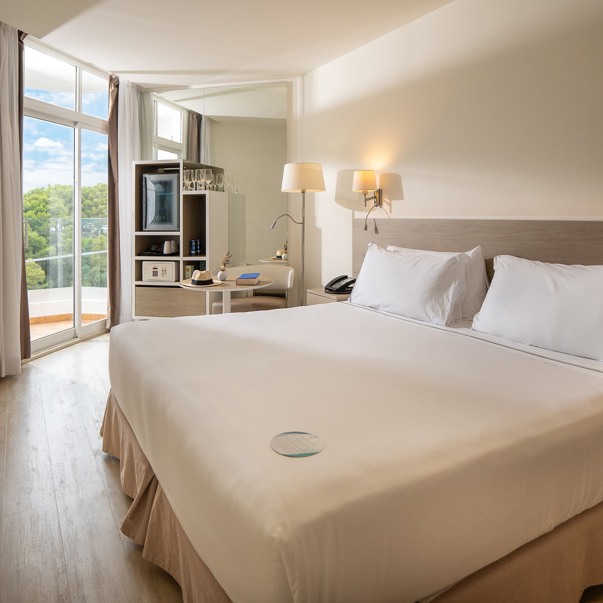 a bed with white sheets and lamps in a room with a glass door