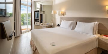 a bed with white sheets and lamps in a room with a glass door