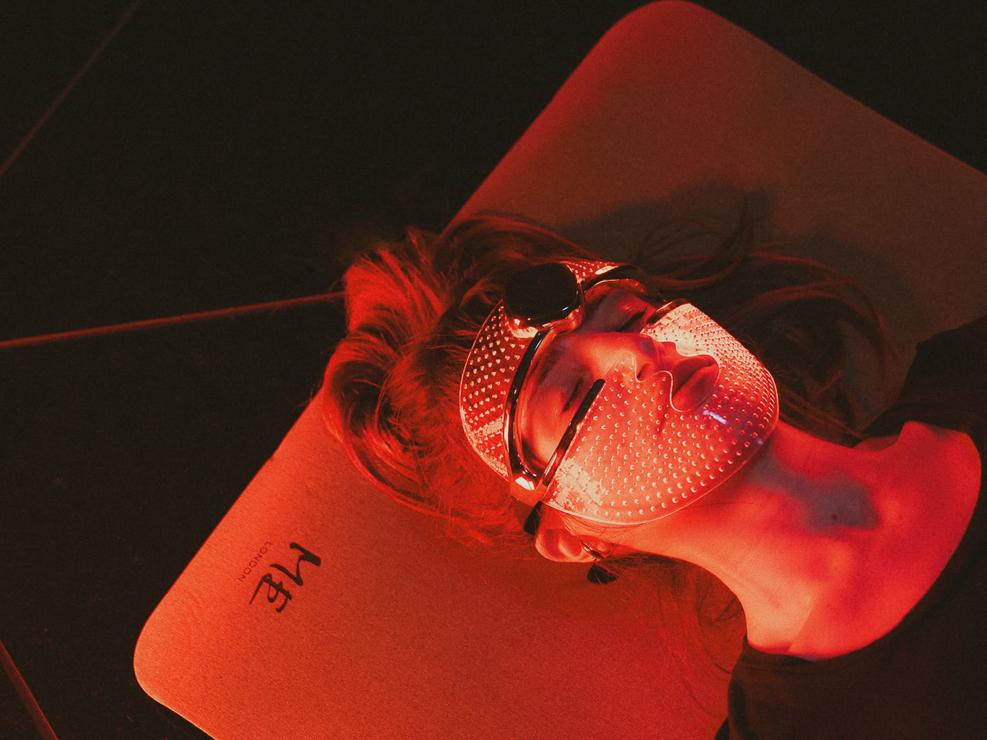 Red LED light therapy mask on person for facial skincare treatment.
