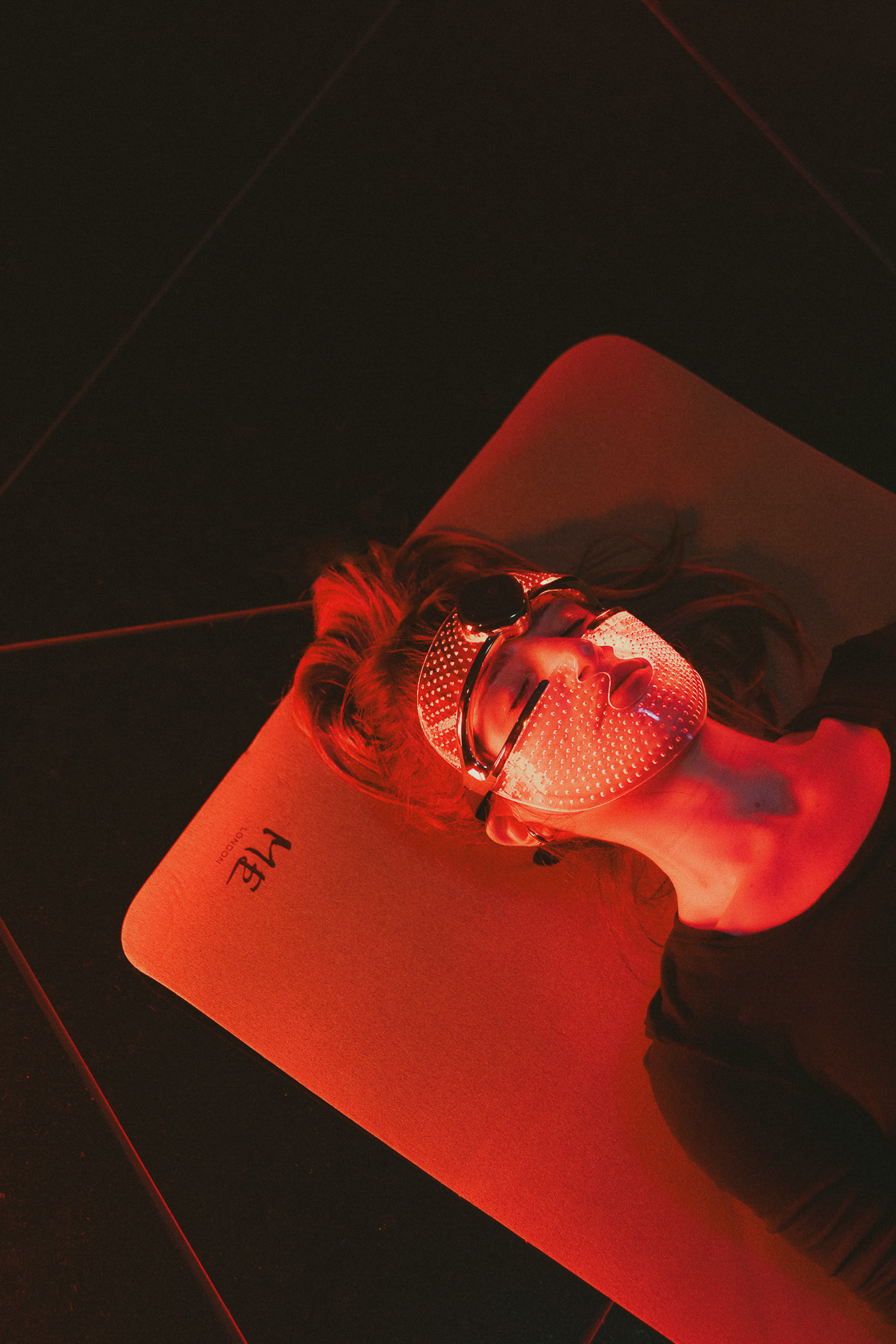 Red LED light therapy mask on person for facial skincare treatment.