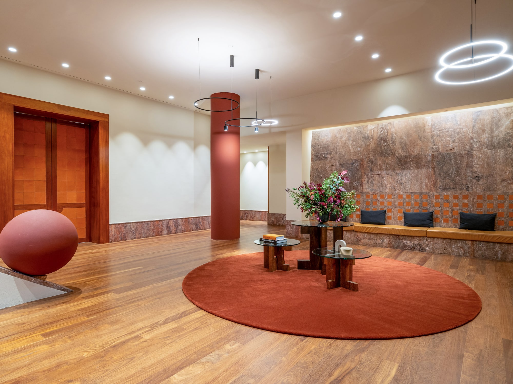 a room with a round red rug and a round table with flowers