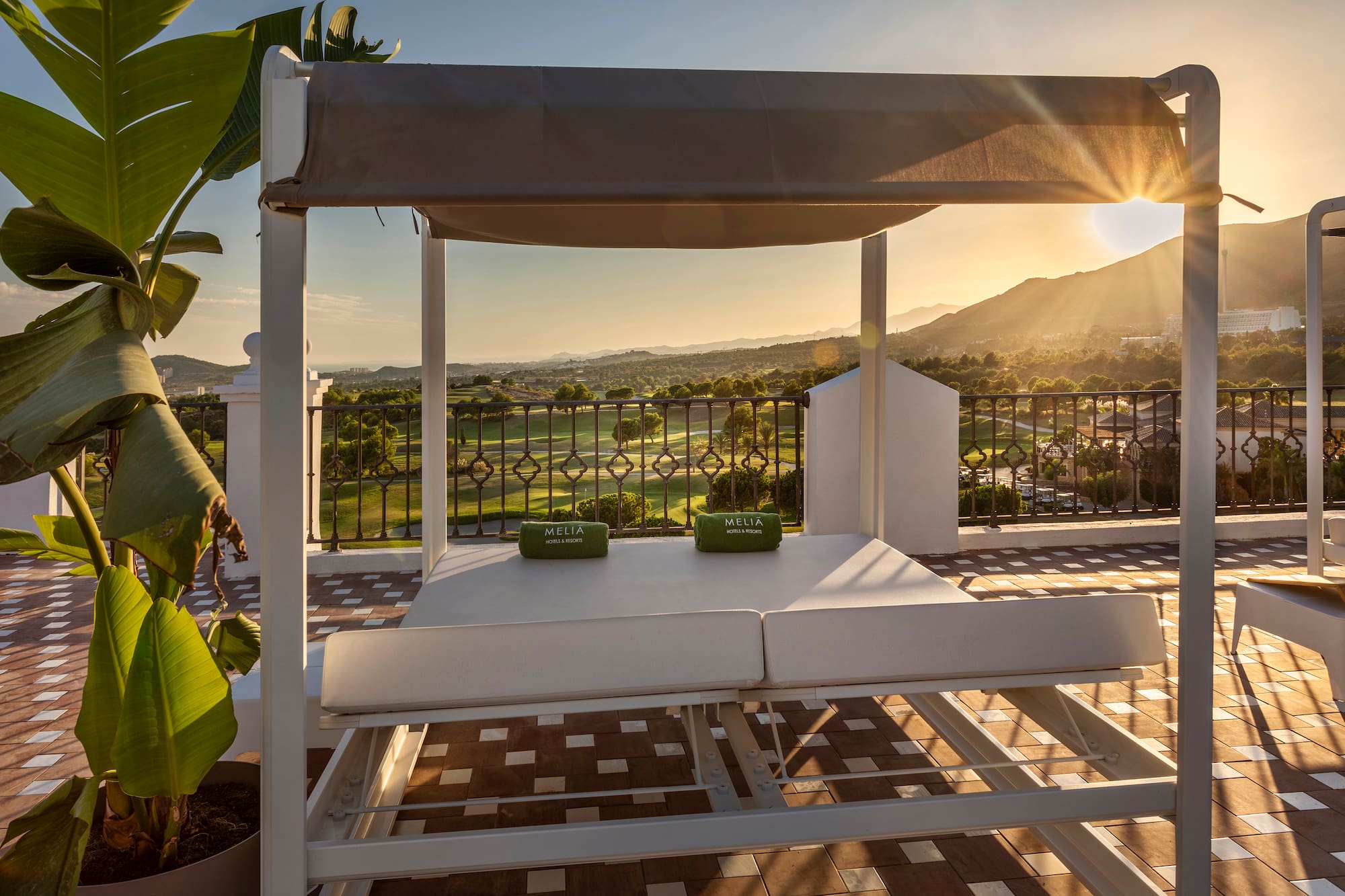 Meliá luxury daybed on terrace, golf course, mountain view at sunset.