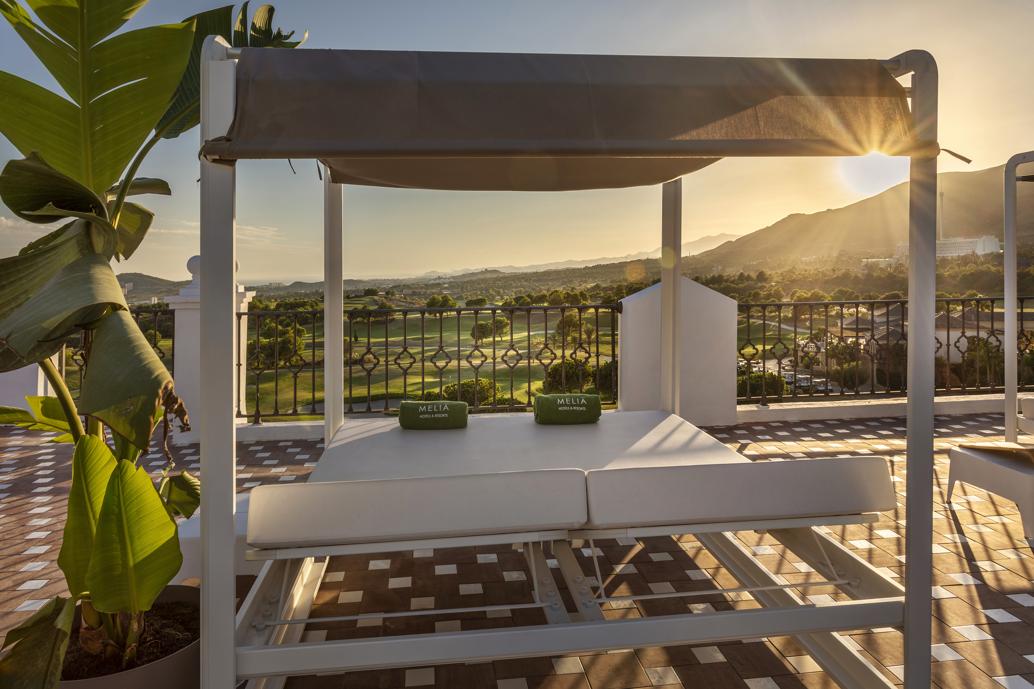 Meliá luxury daybed on terrace, golf course, mountain view at sunset.