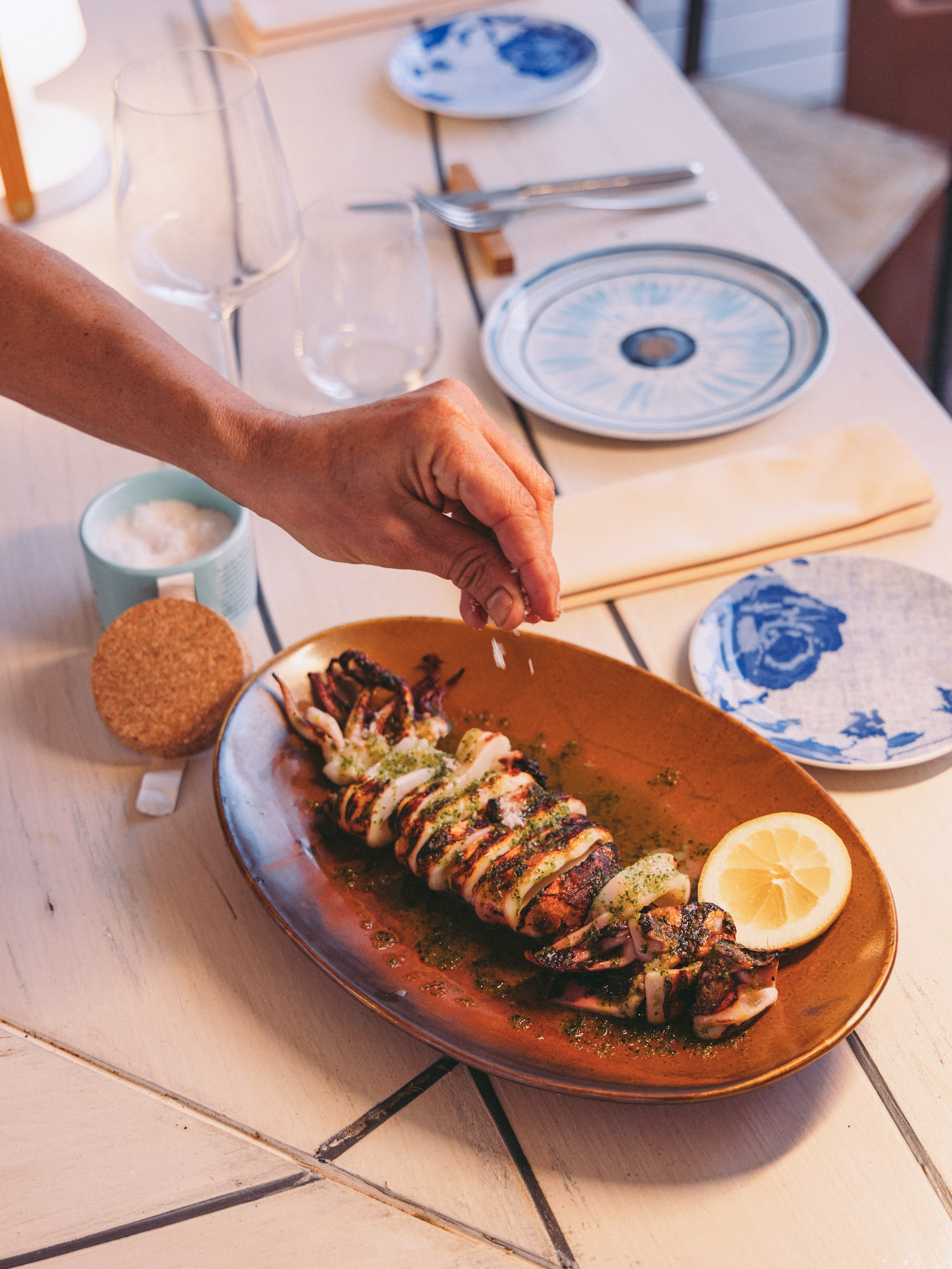 a person sprinkling a piece of food on a plate