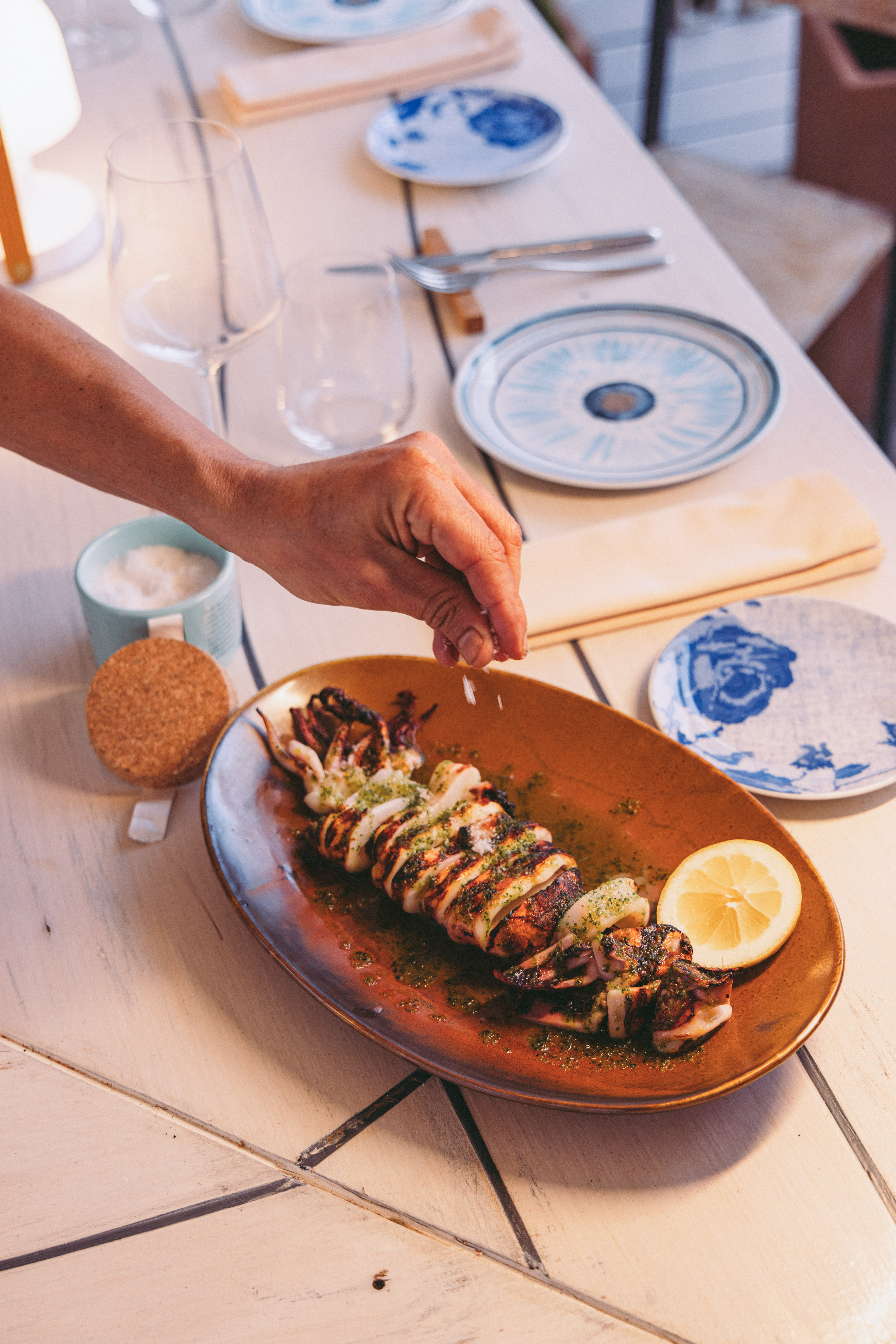 a person sprinkling a piece of food on a plate