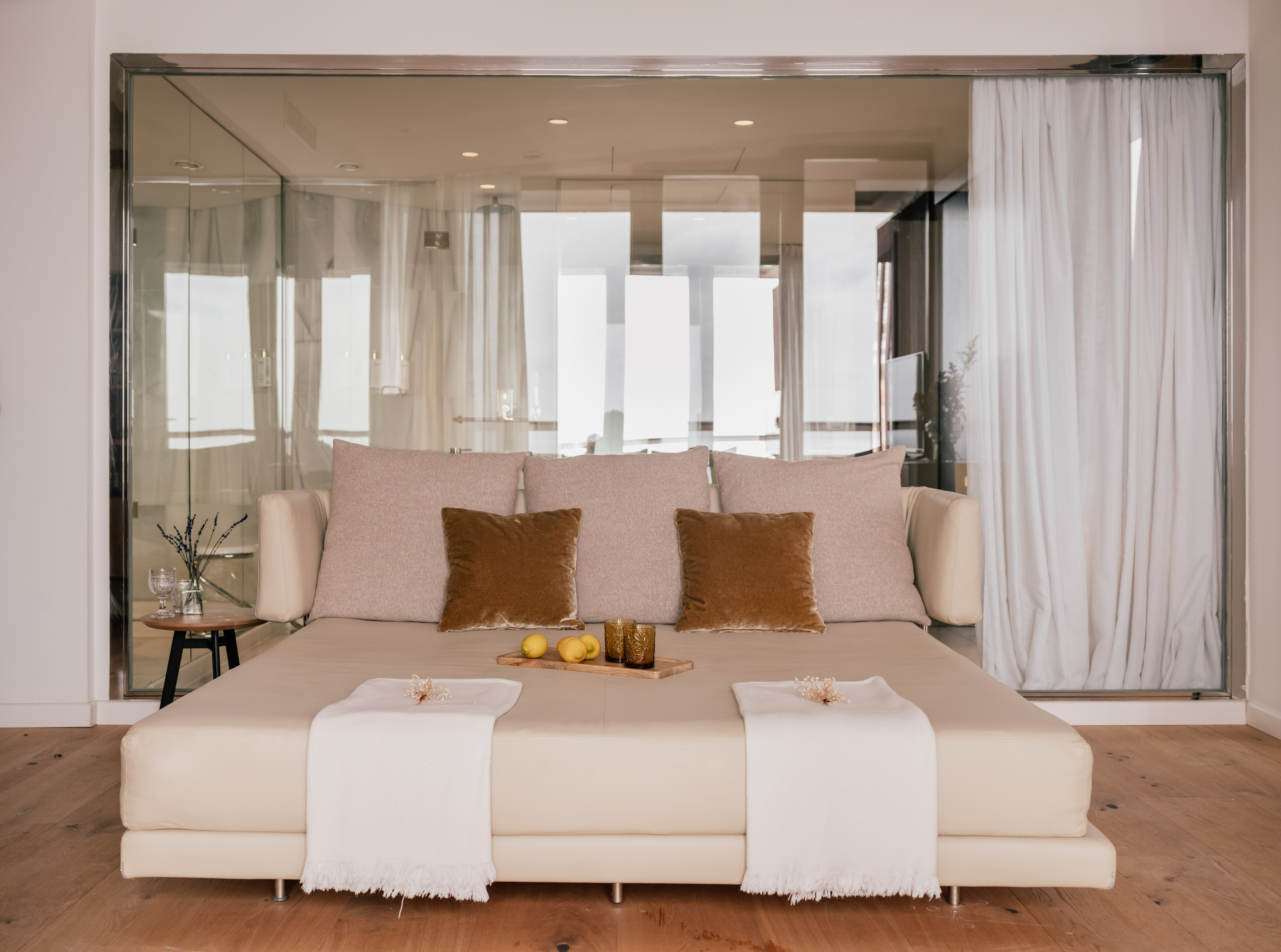 Cream daybed, neutral pillows, lemons, white throws. Modern hotel spa lounge.