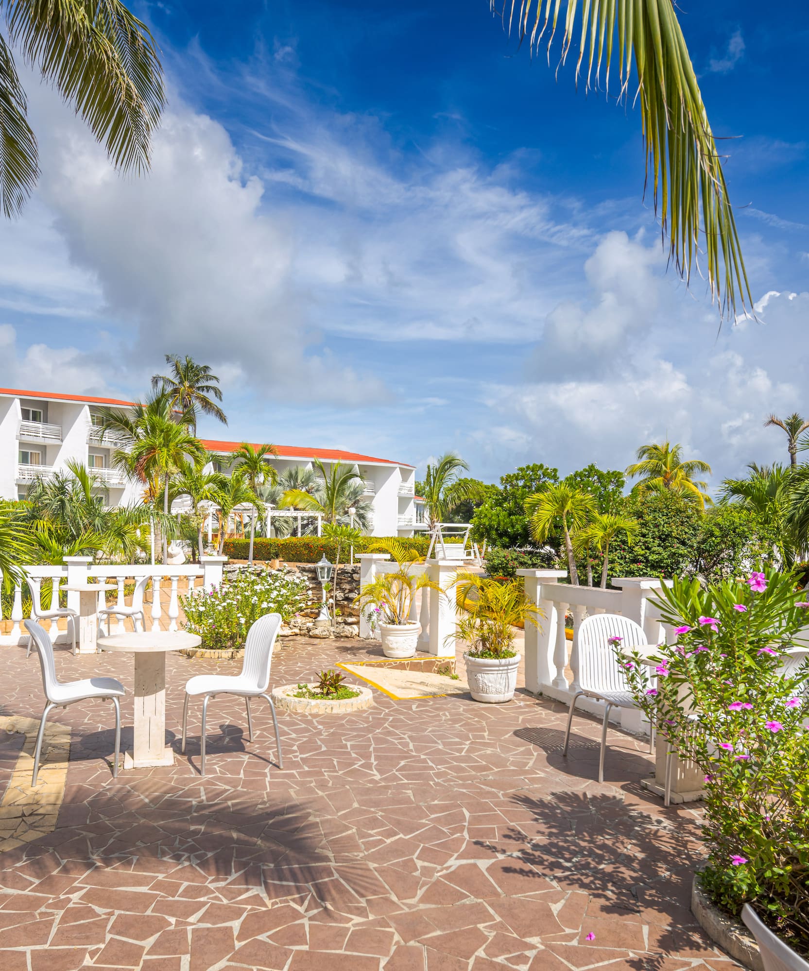 a patio with white chairs and trees